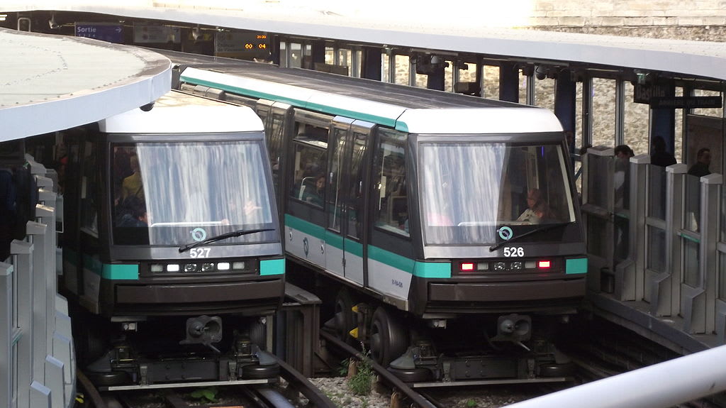 Two Paris subway trains carry passengers along tracks.