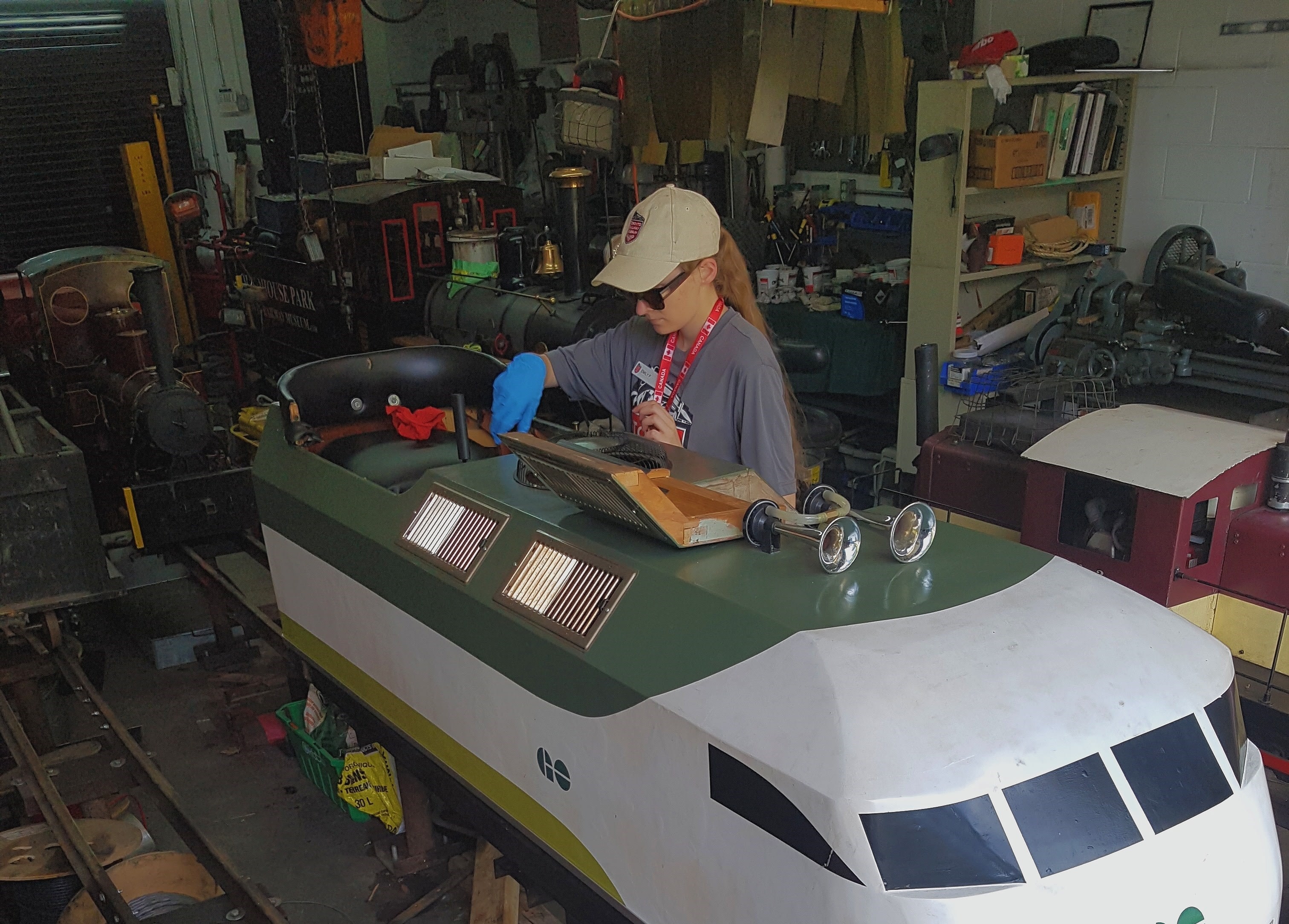 A worker checks under the hood of a mini GO train.