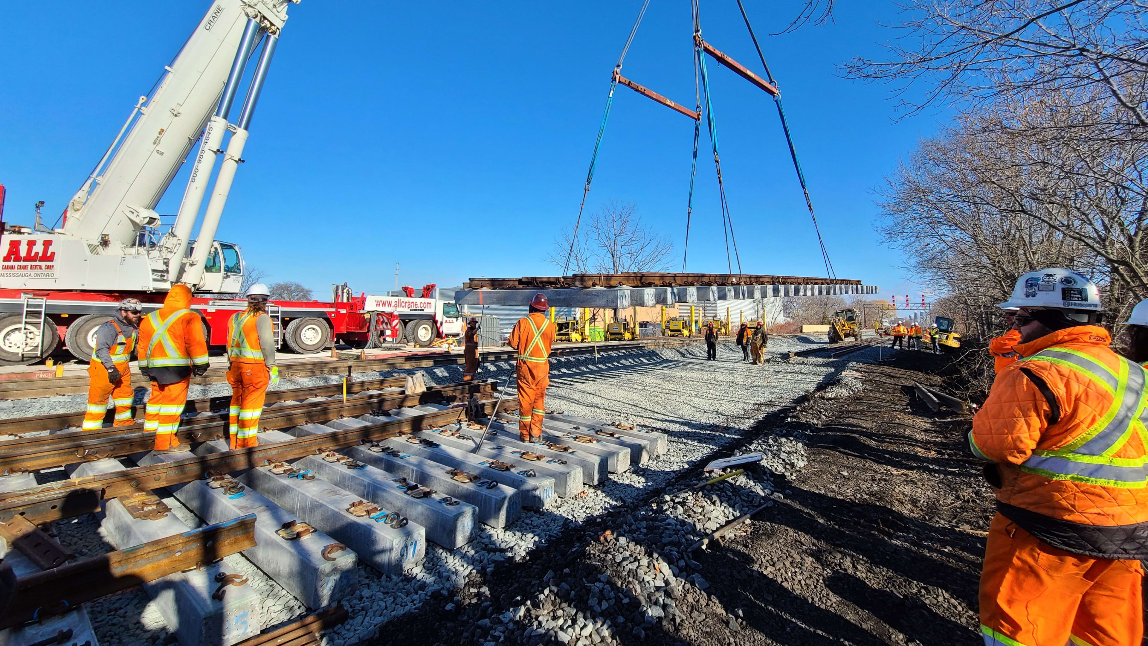 Construction crews use a large crane to place new tracks along the Lakeshore West Line near Long ...
