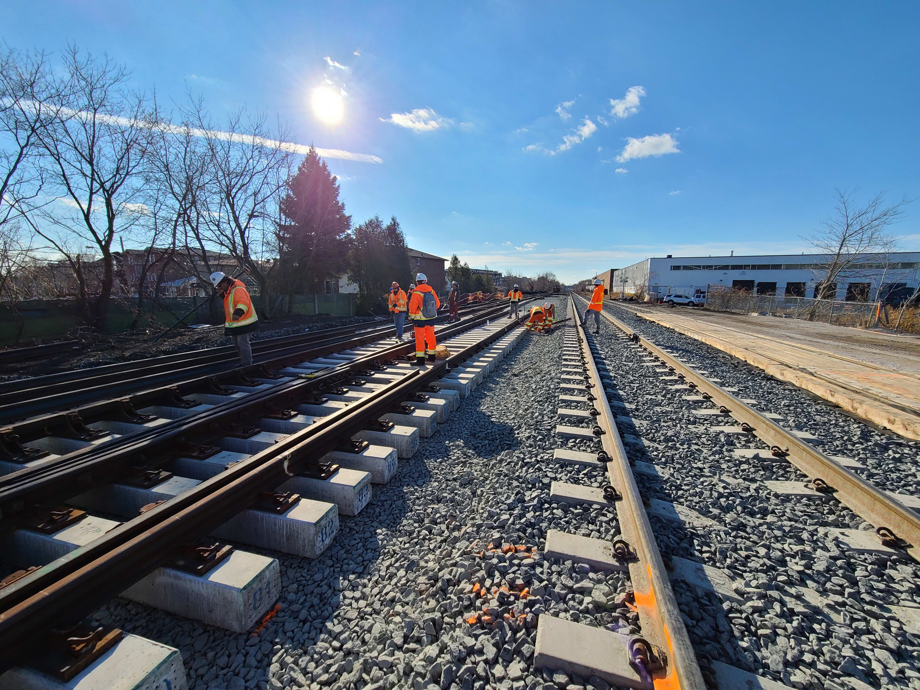 Workers install and inspect large sections of track