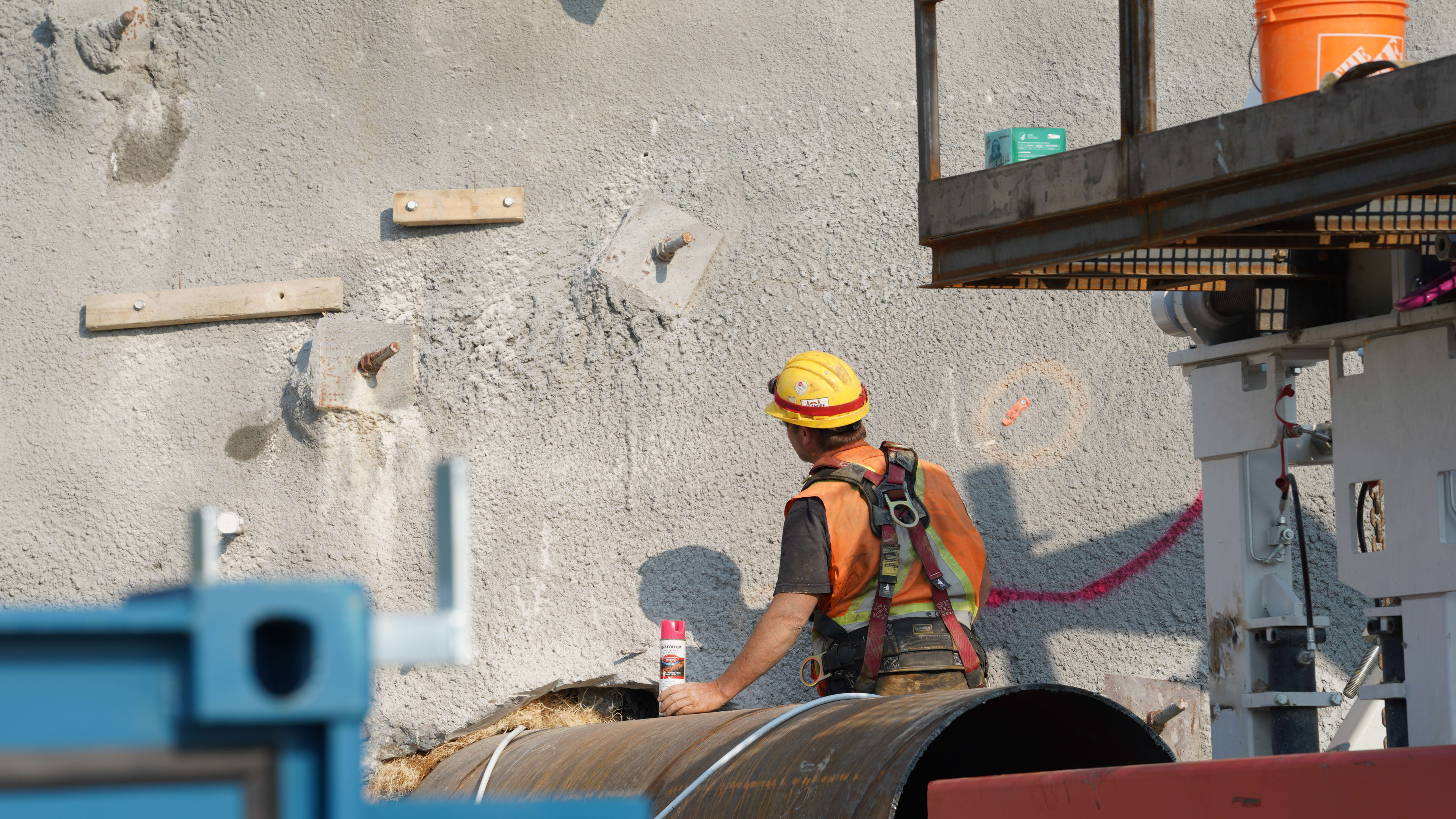 A worker looks closely at a wall of concrete, in preperation of work to come.