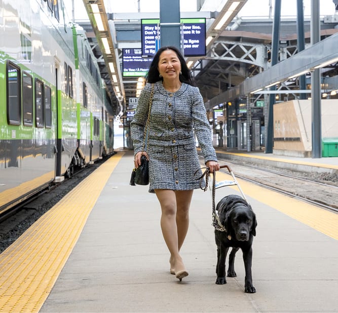 A passenger walking on a train platform with a service dog