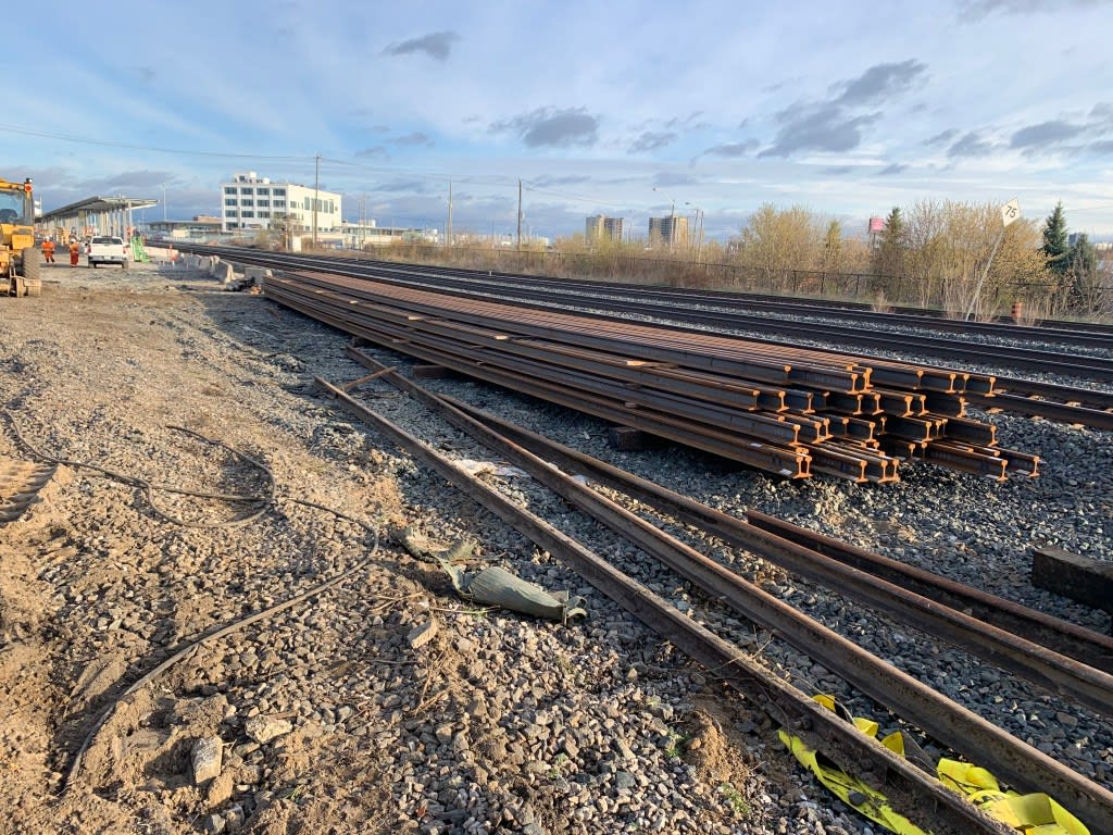 A pile of tracks rests beside a rail line.
