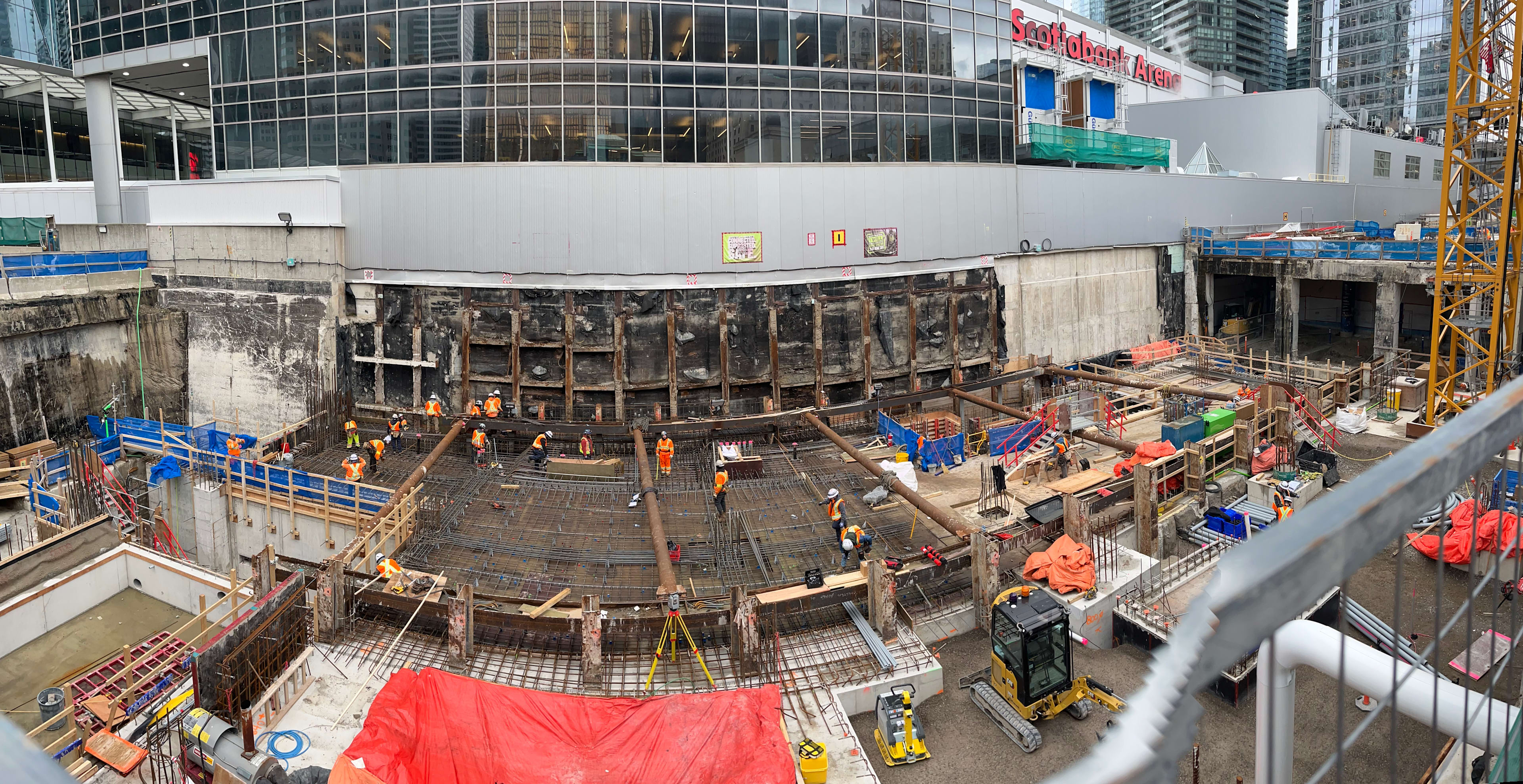 A group of construction workers scattered throughout an outdoor job site.