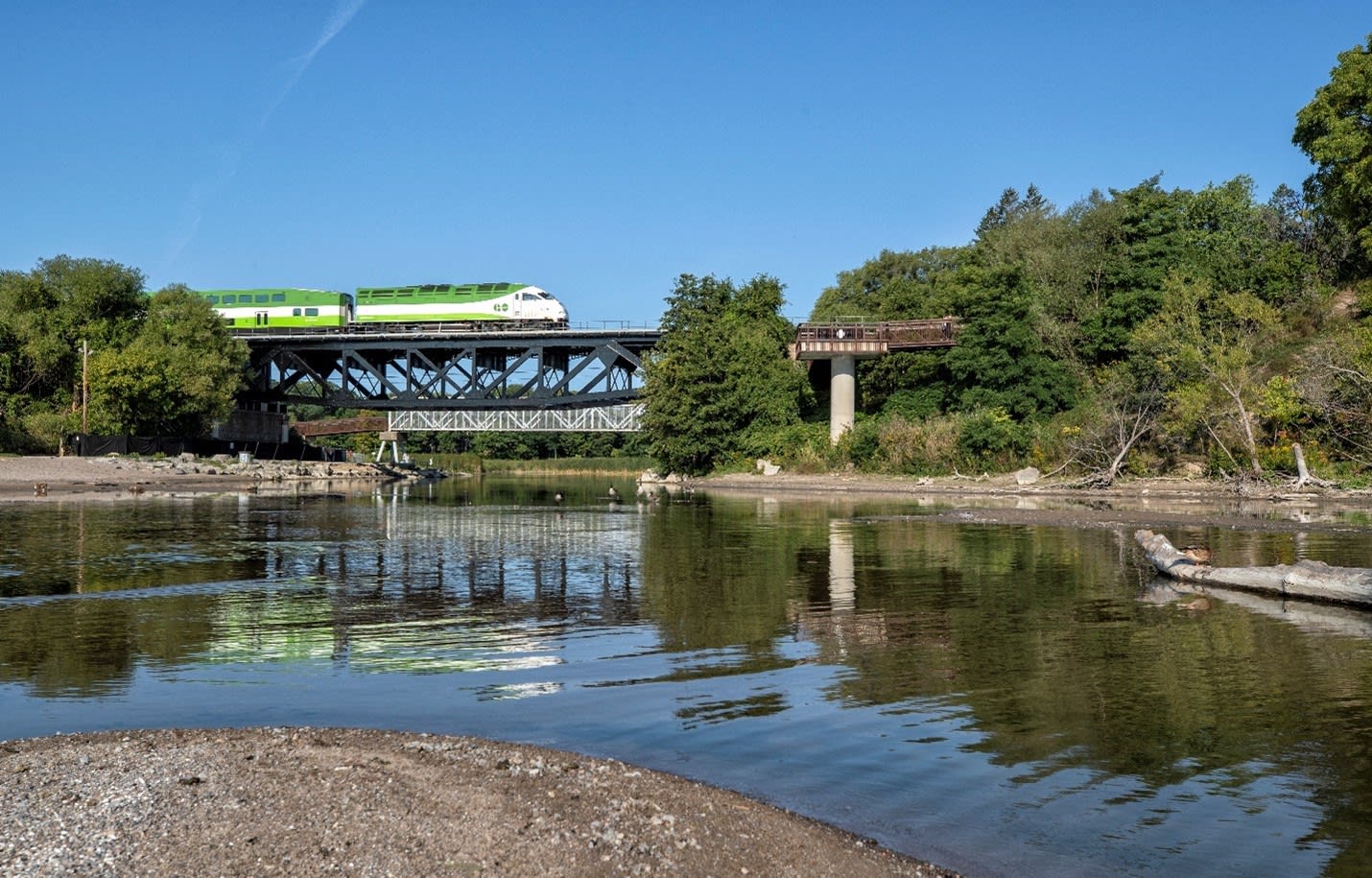 A GO Train rides over an upgraded bridge, crossing the Rouge River