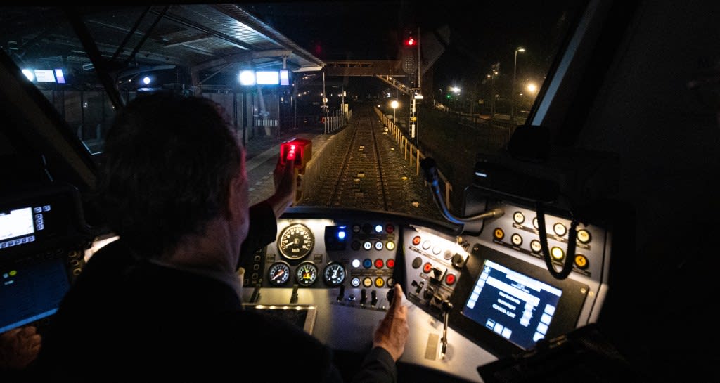A driver sits at the control panel of a train.