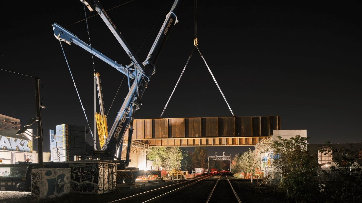 A large crane lifting metal beams at night
