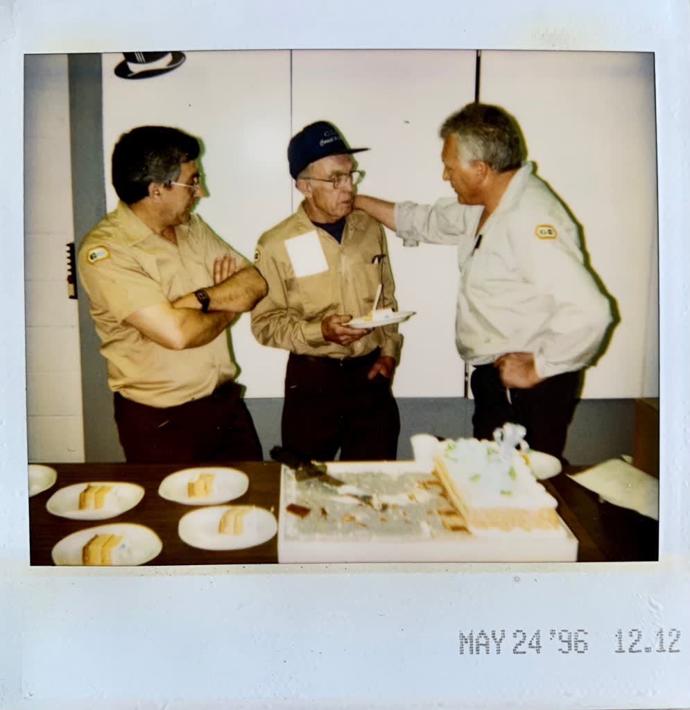 a polaroid of the Fred Bentley enjoying a slice of cake with coworkers.