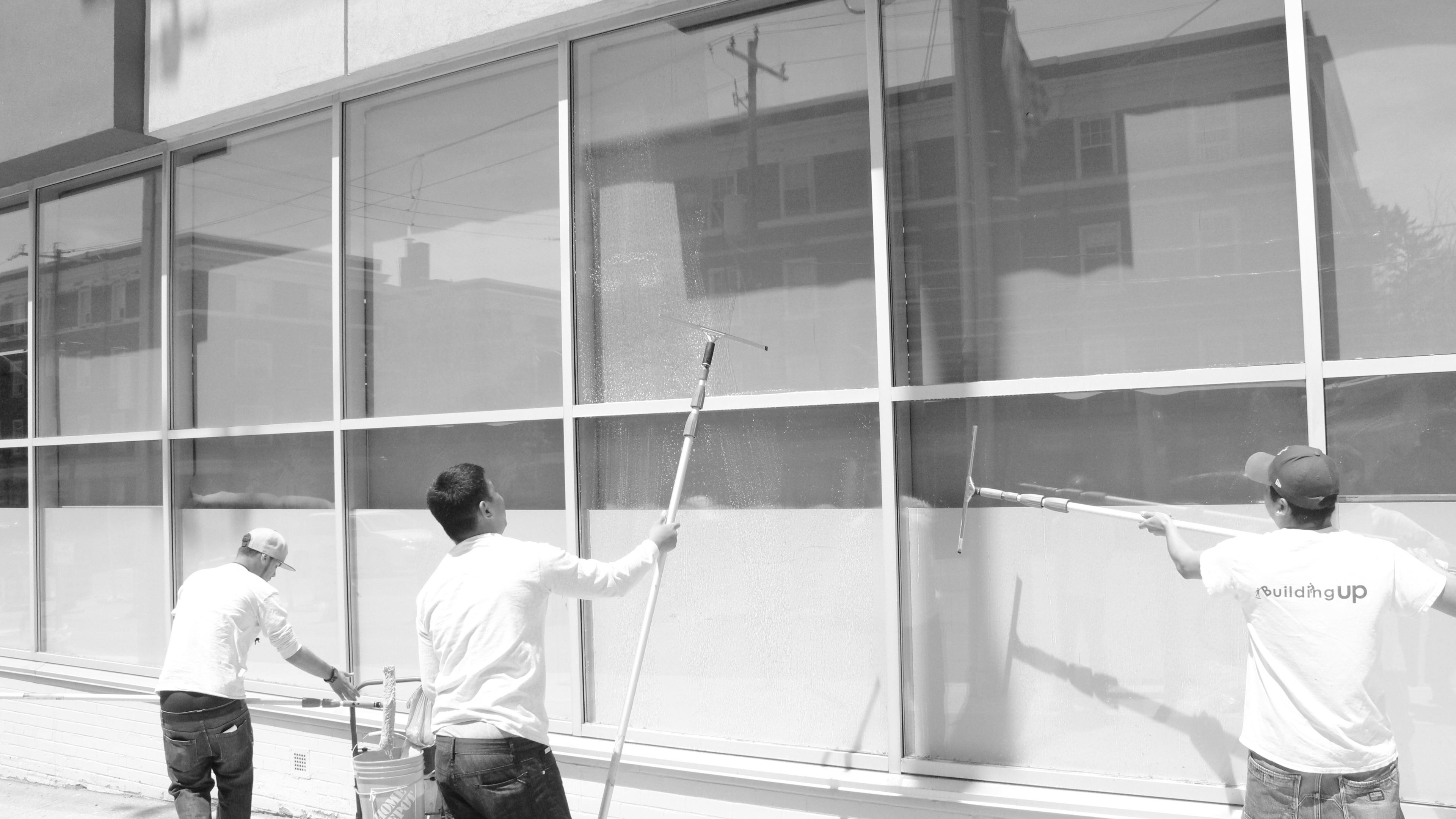 Window washers work on Eglinton Ave washing windows of street front businesses