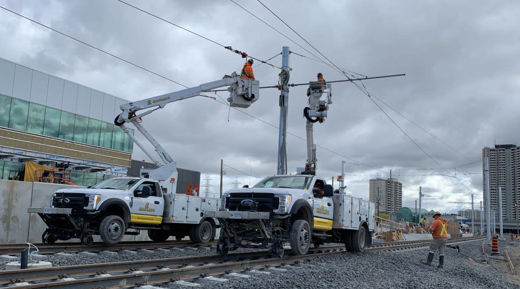 crews working in cherry-pickers above the tracks.