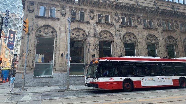 a TTC bus going by a building at Queen and Yonge in downtown Toronto.