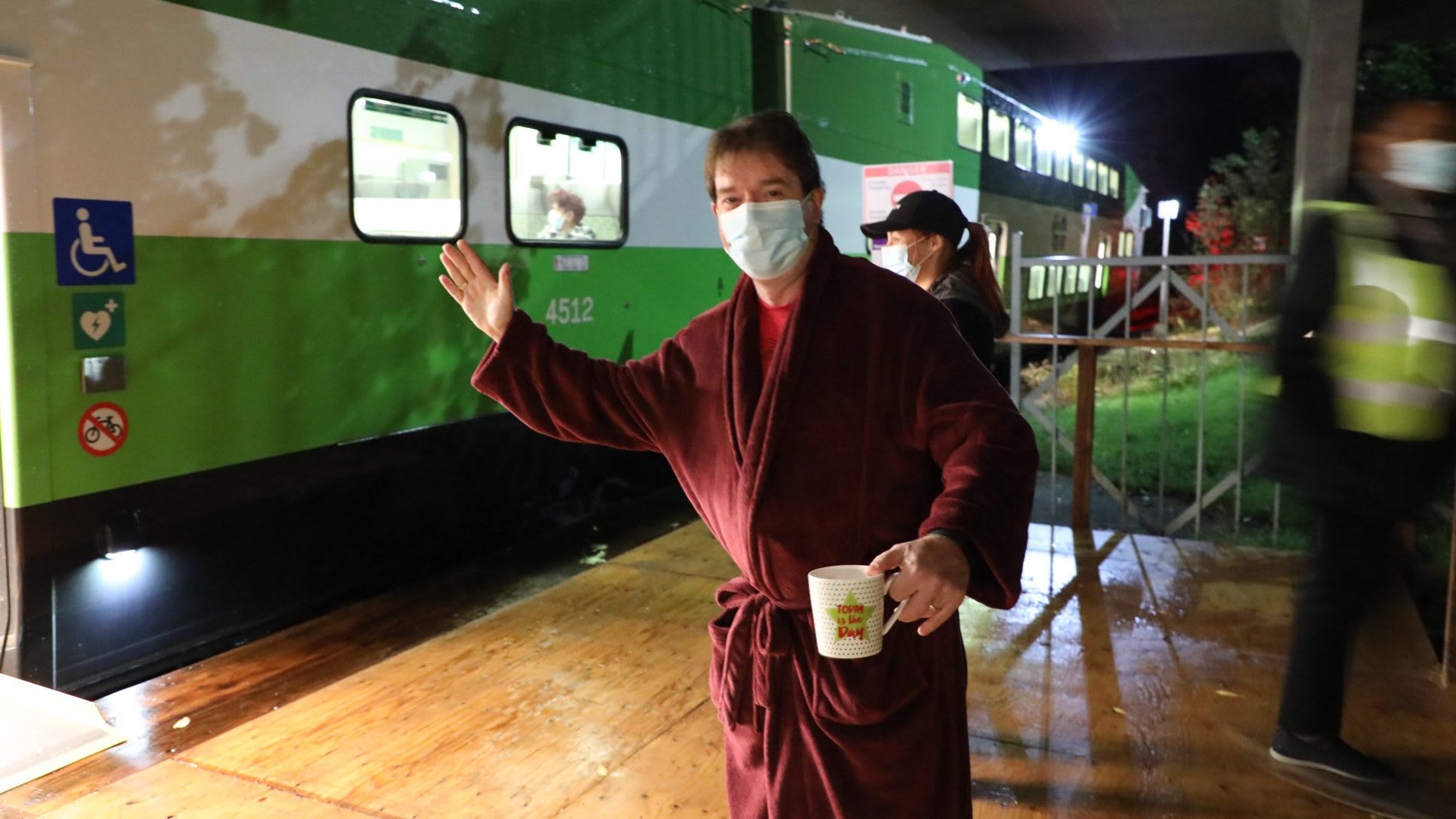 Mayor stands in a robe, holding a coffee