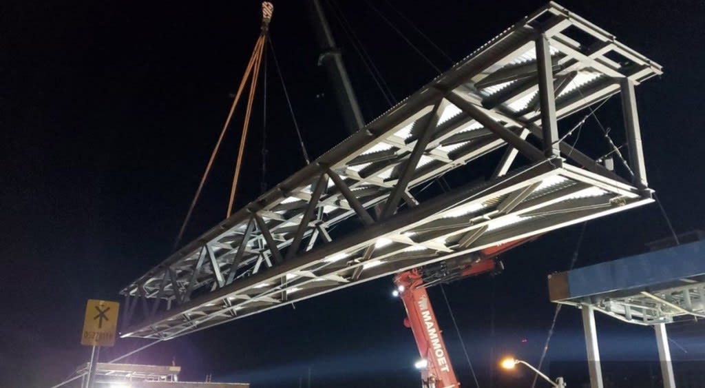 After rigging the bridge to the crane and performing the required safety checks, the pedestrian b...