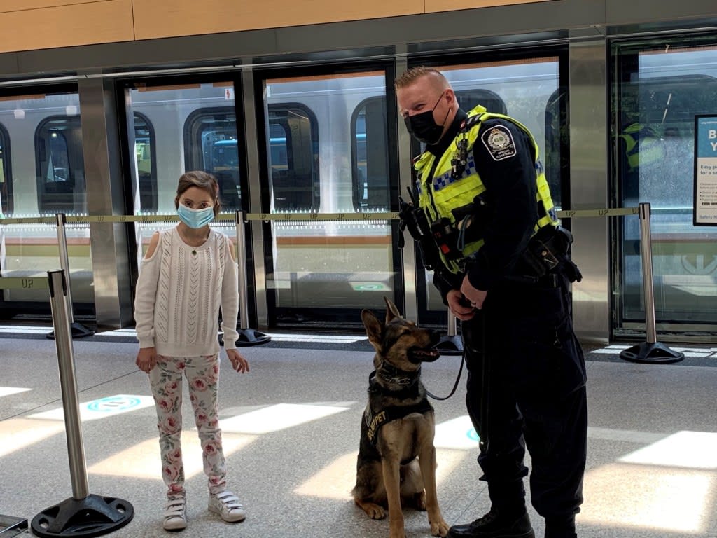 Romina stands next to a GO Transit Safety officer and his K9 partner at the UP Express terminal a...