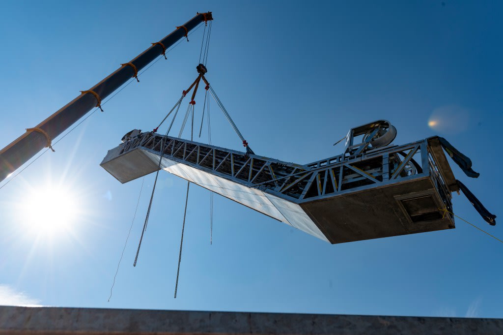 An escalator is raised by a crane.