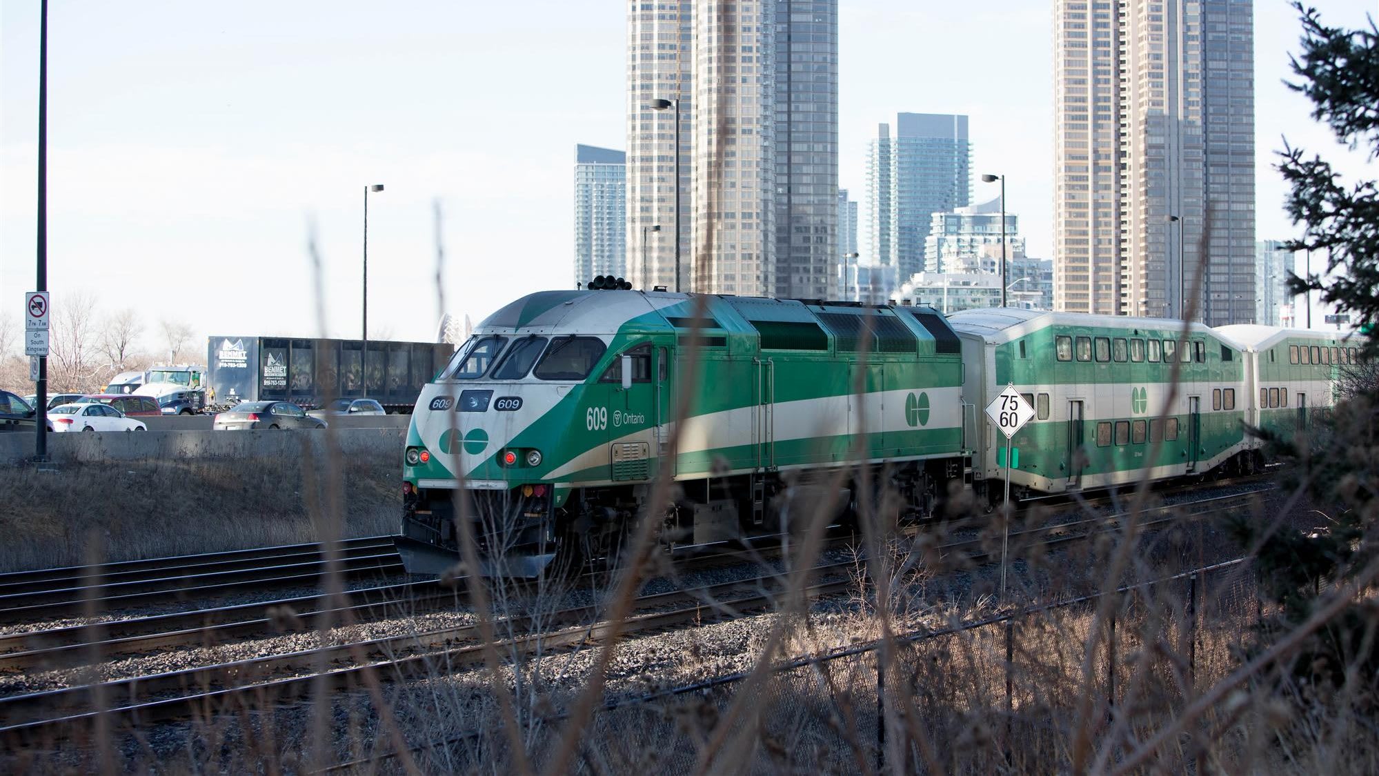 GO train running along the Lakeshore West Line next to the gardiner