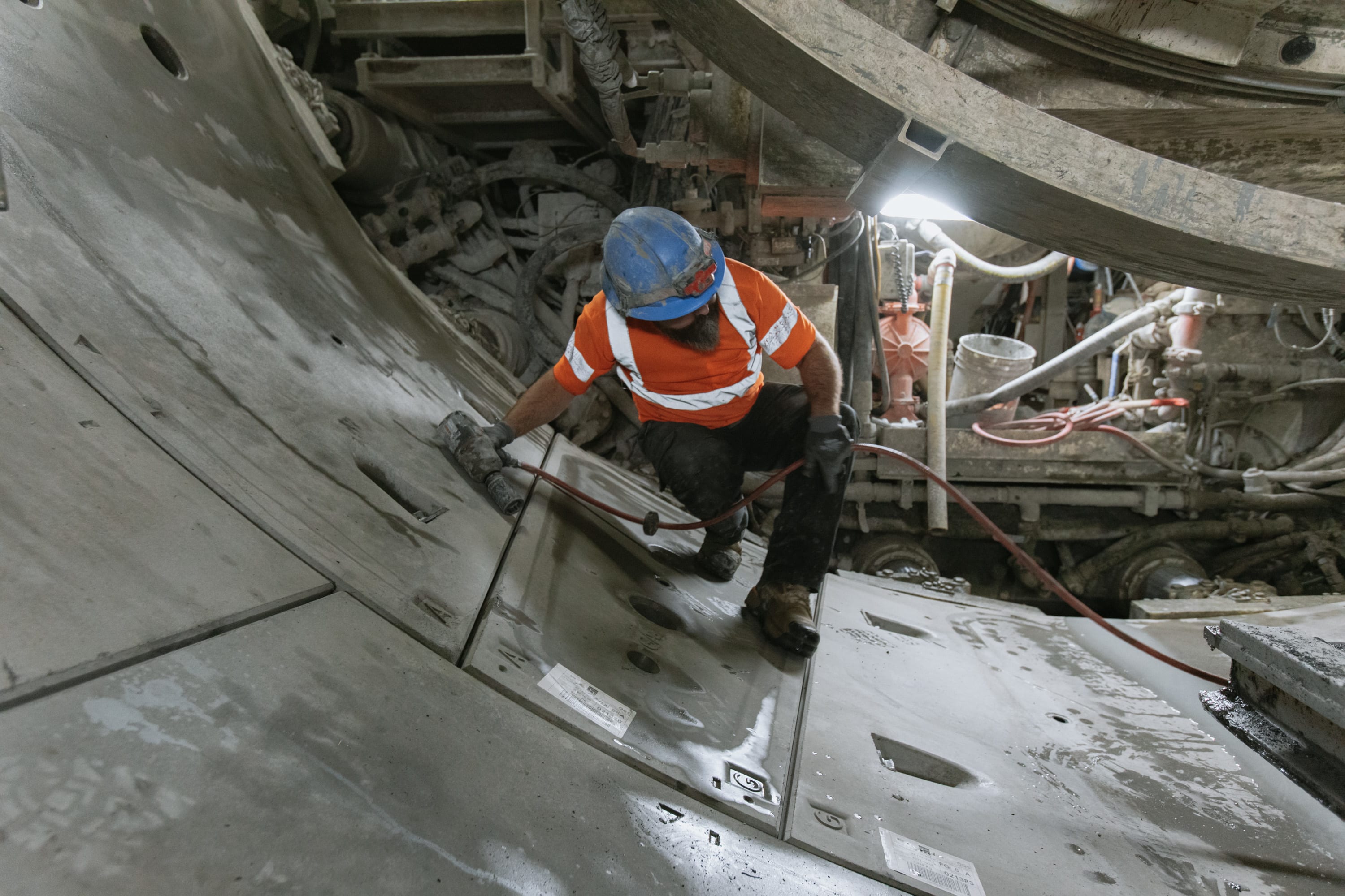 A worker inspects recently installed tunnel wall segments for the Eglinton Crosstown West Extension.