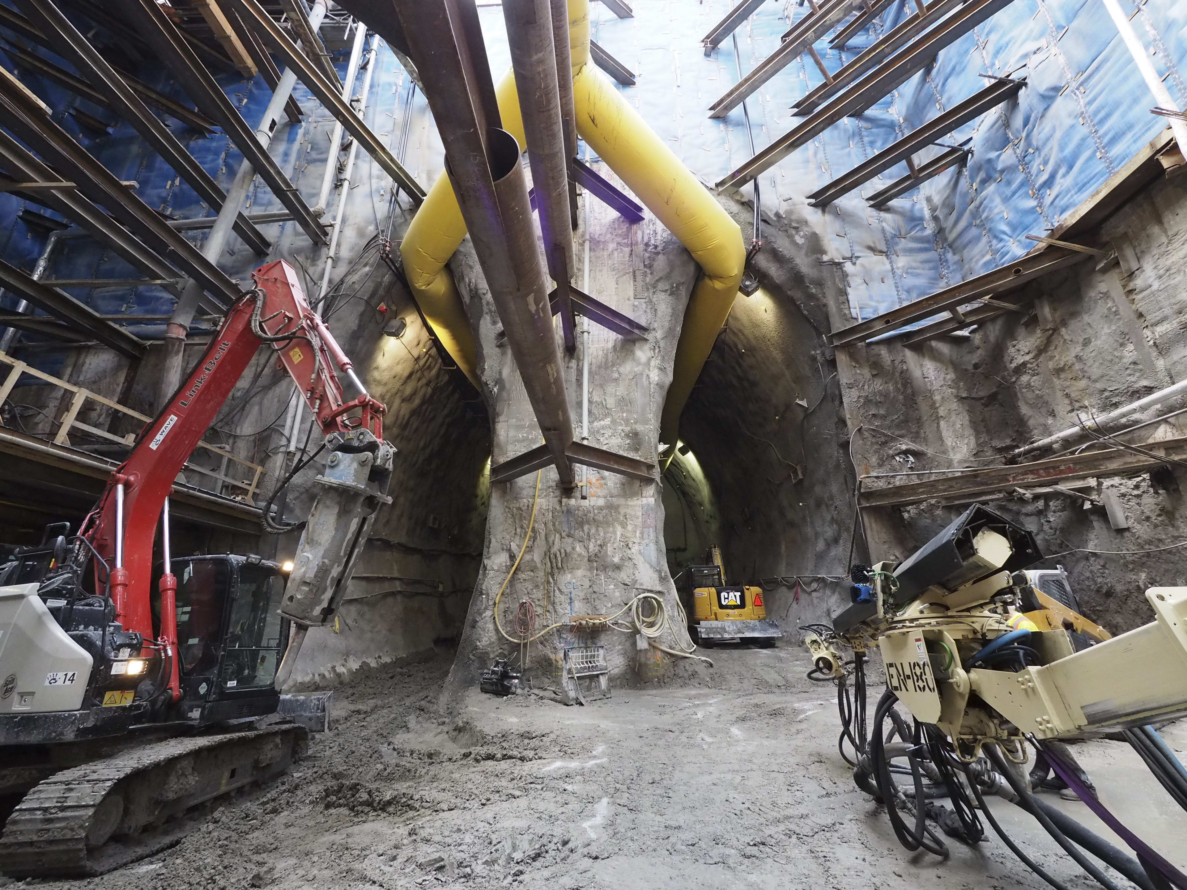 Inside a large cavern, machinery works to dig away at holes.