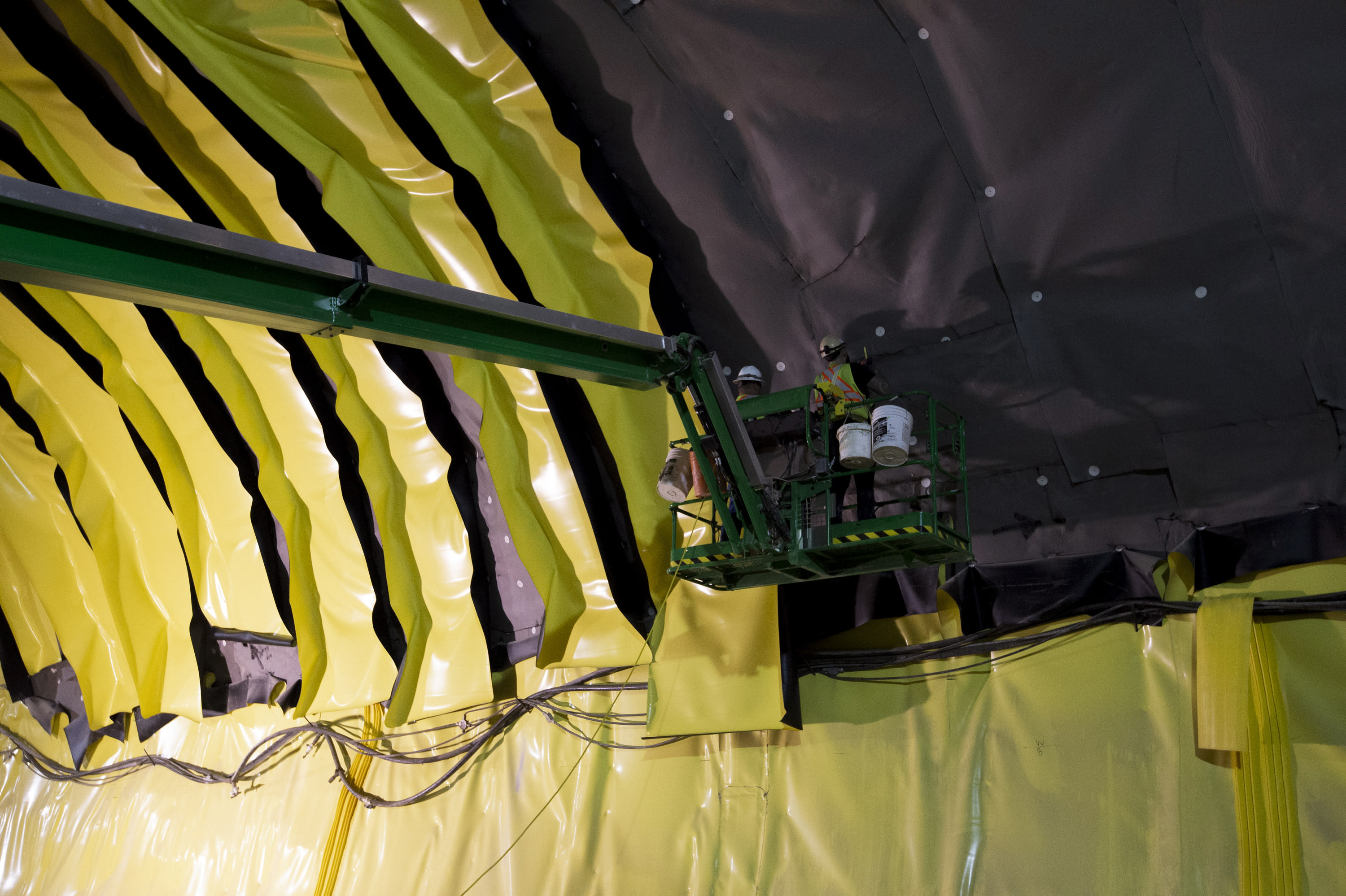 Crews work to install yellow waterproofing strips on the inside of the Avenue Station tunnel.