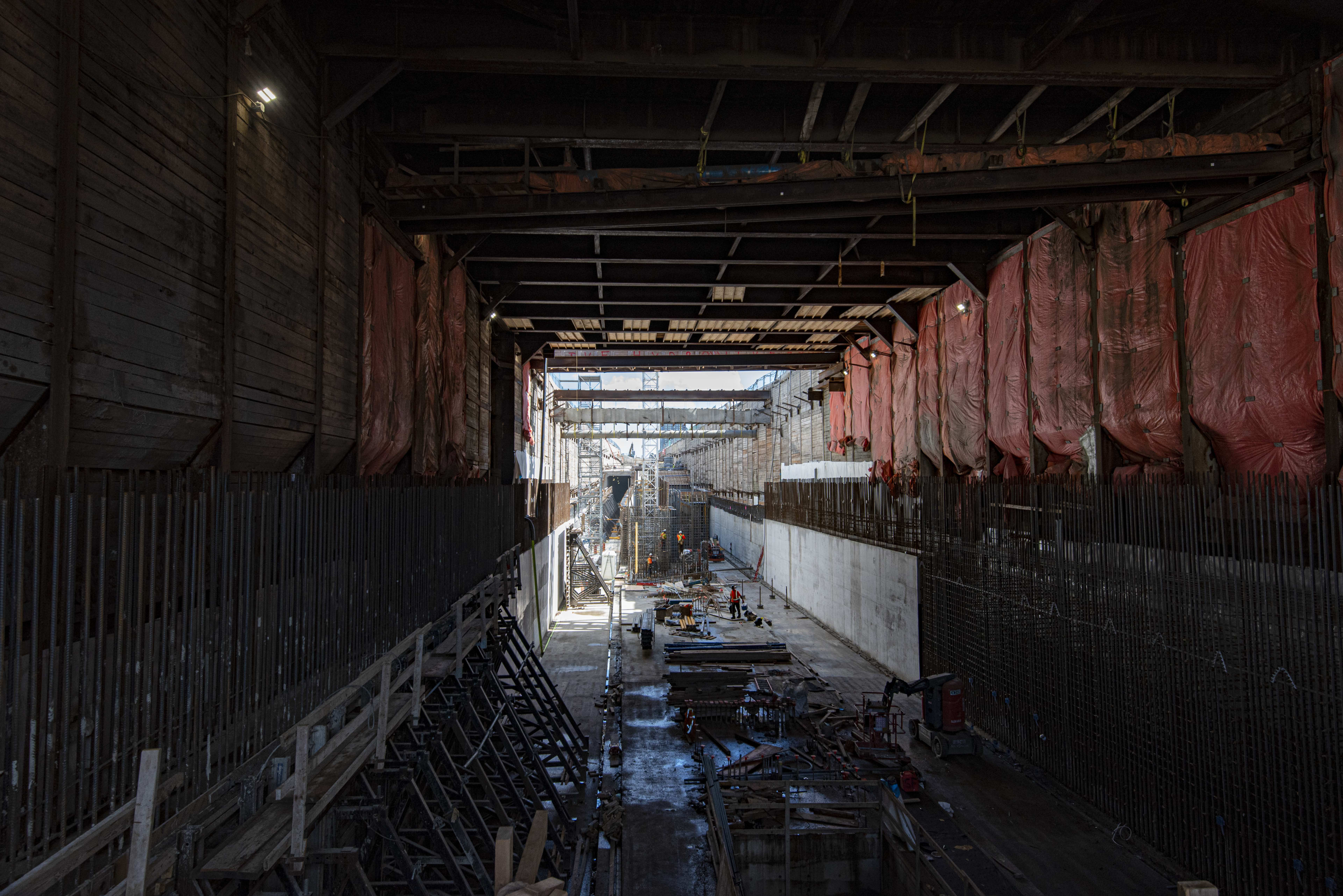 Crews work deep in the concrete tunnel. Light is seen at the far end.
