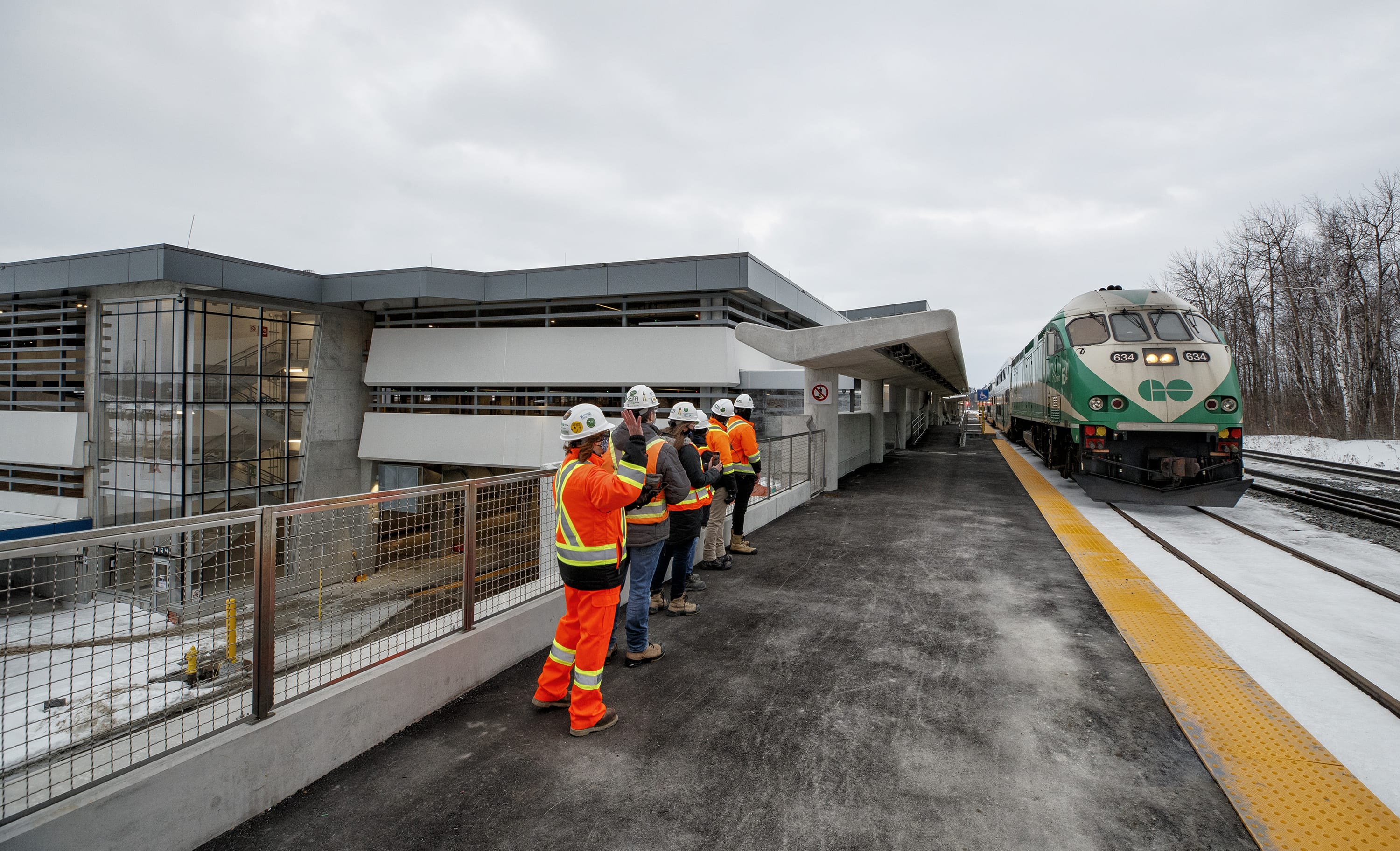 A GO train pulls slowly in as staff stand on the platform.
