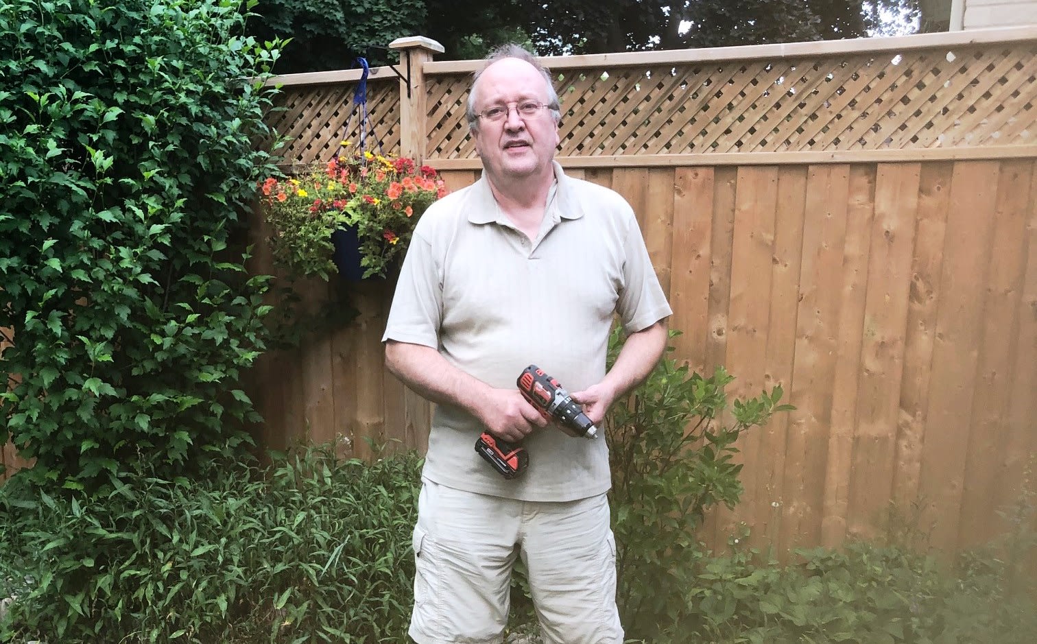 Chris standing in his backyard garden holding a drill
