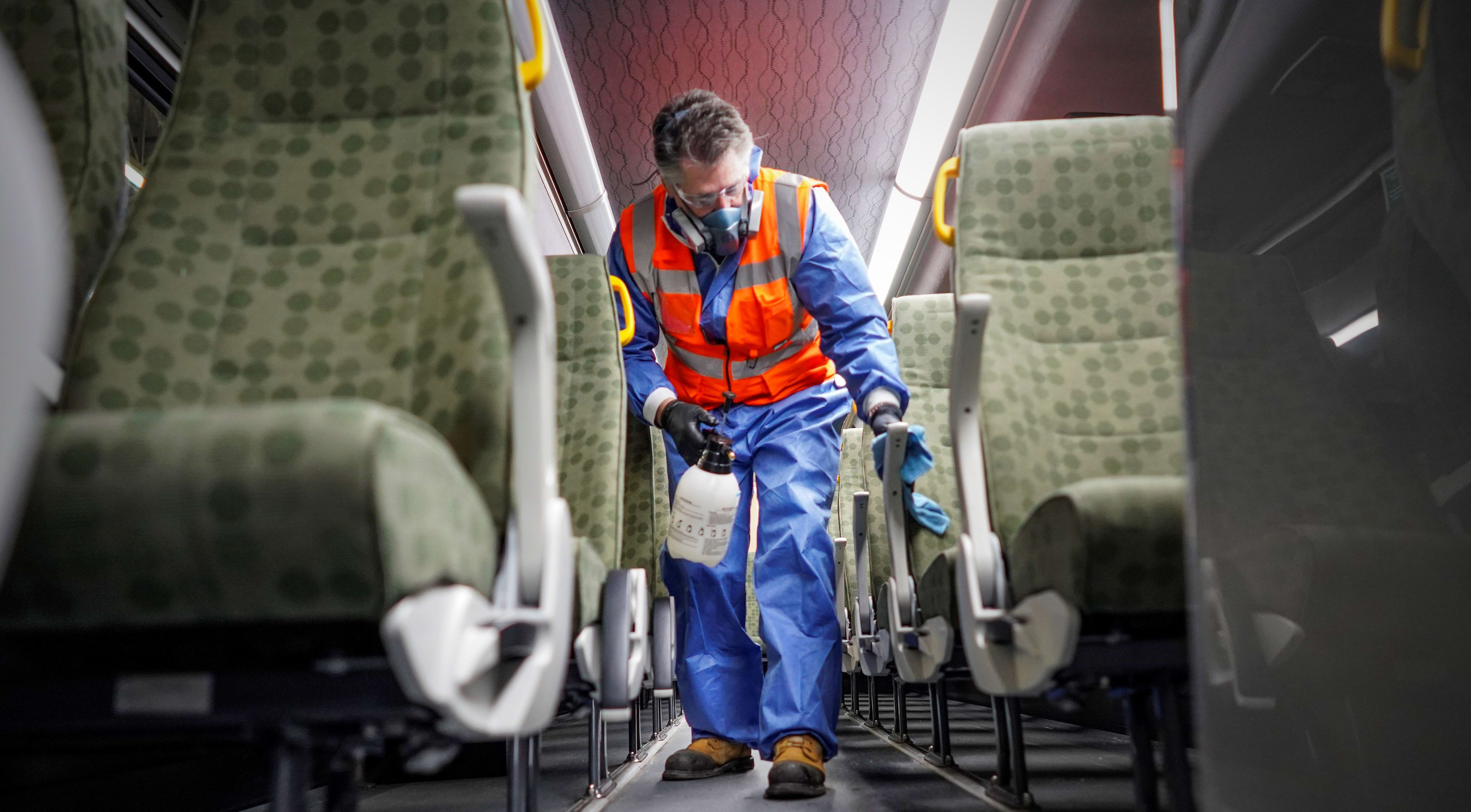 A man wipes down GO bus seats.