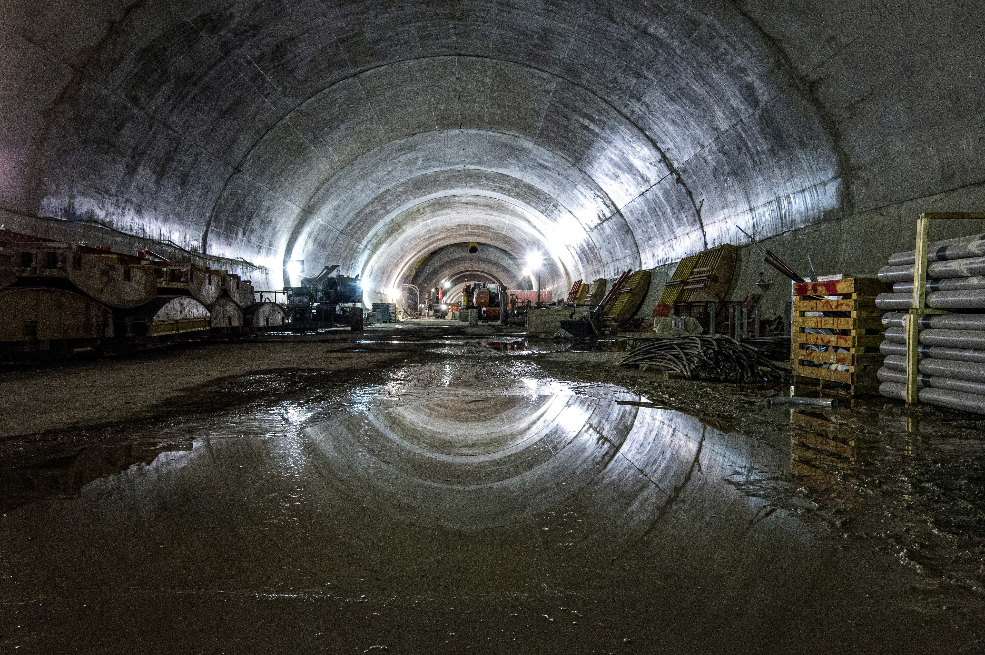 a puddle of water reflecting the top of the concrete tunnel.