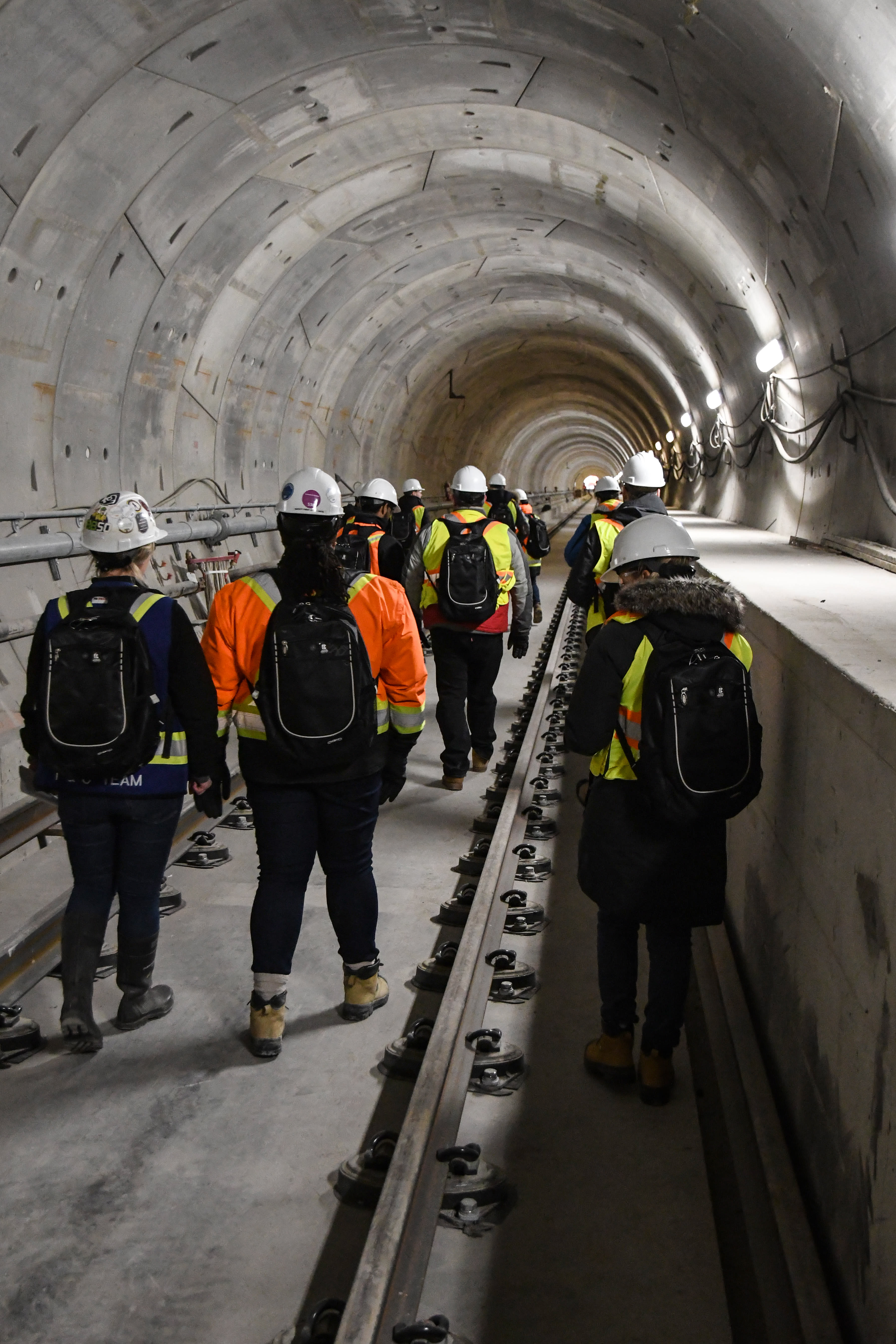 A group of people walk down through a concrete tunnel that will be part of the Crosstown LRT.