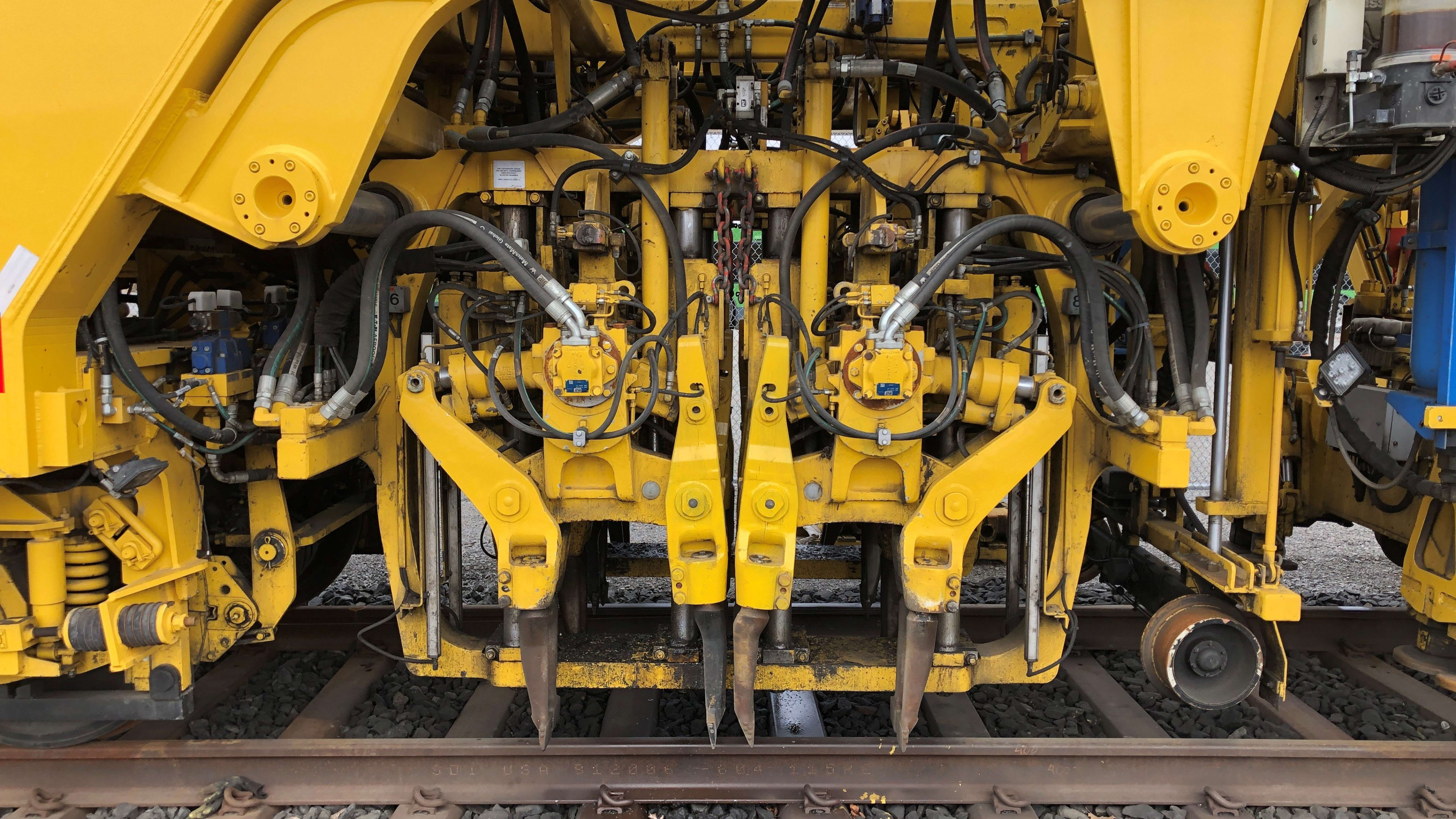 Close up the DynaCATâ??s tamping heads that adjust the rails and ties into the correct position ...