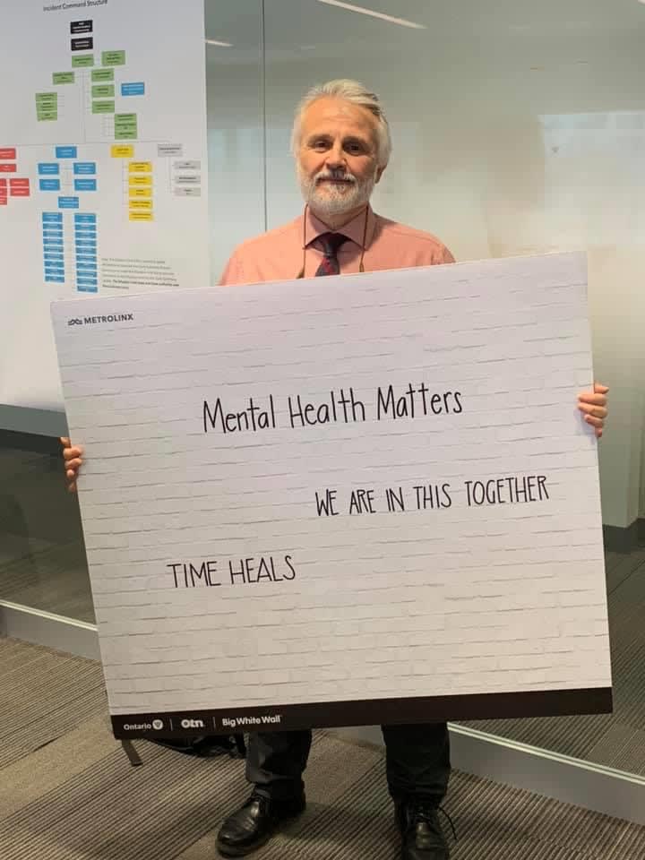 Vito holds up a sign that reads: "Mental health matters - We are in this together. Time heals."