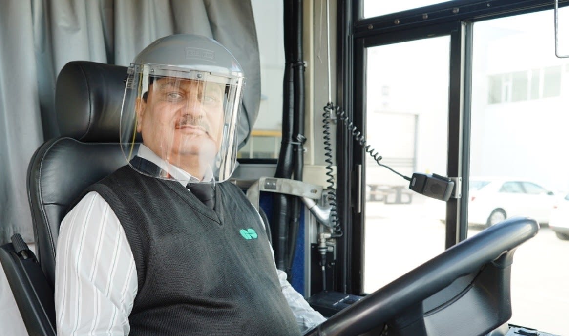 A bus driver wears a face shield.