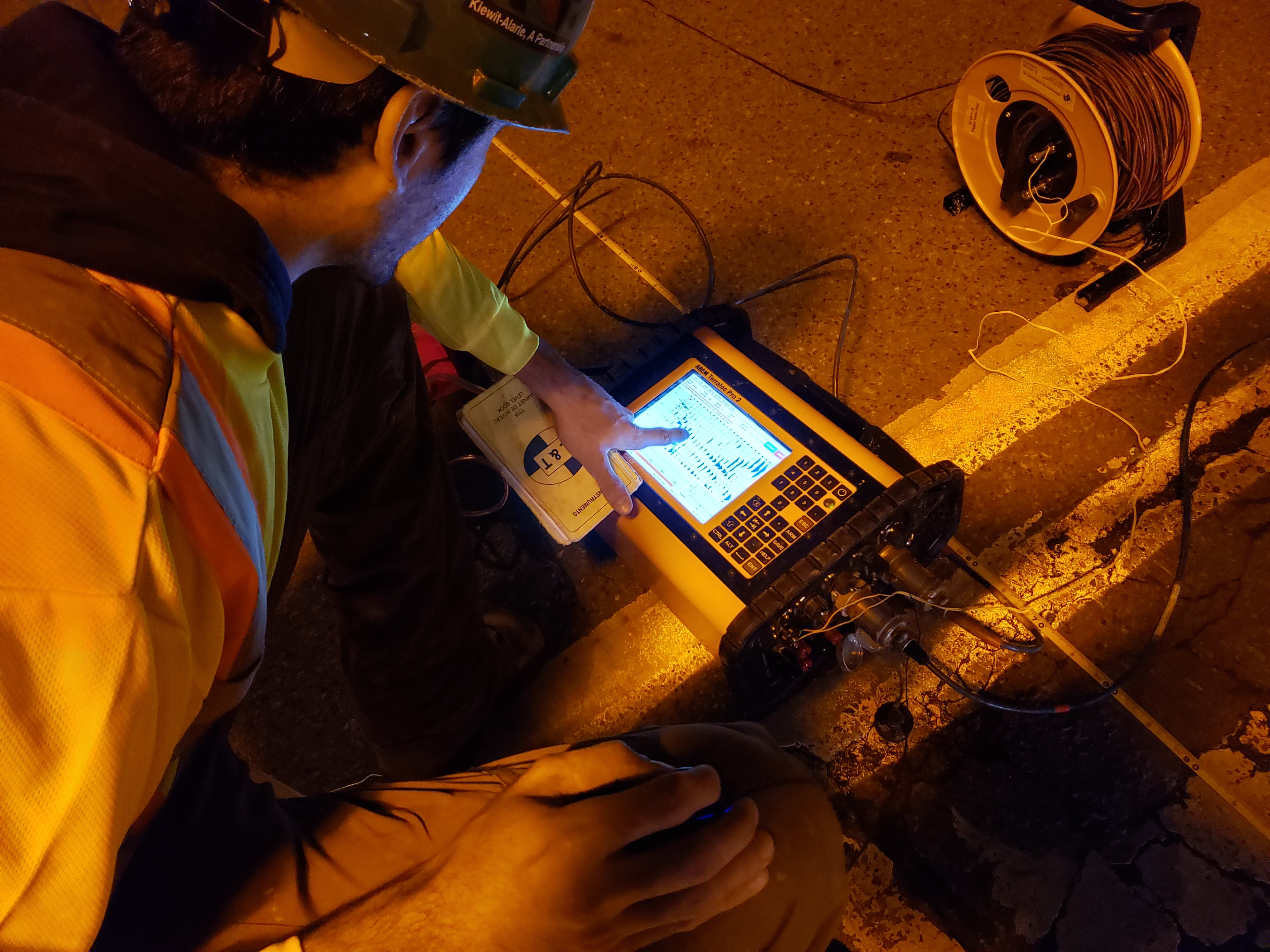 An expert looks at a device used on a street.