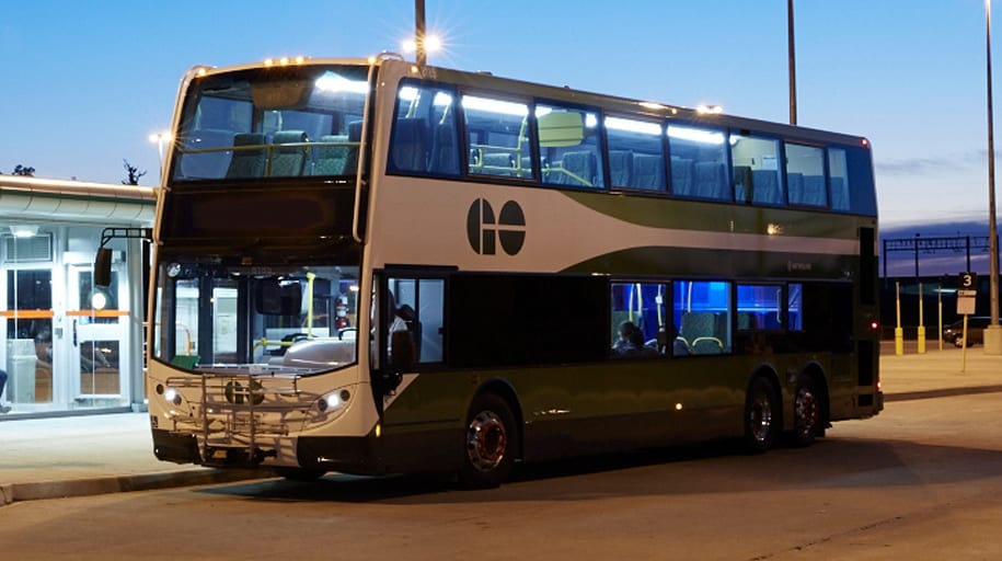 A GO bus waits at a platform in the early morning.