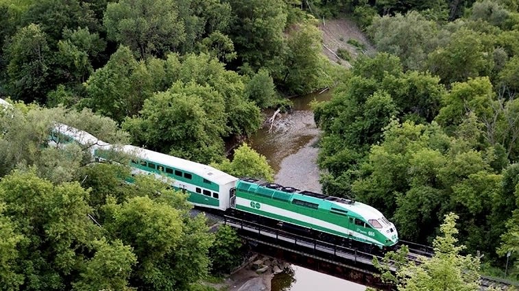 A GO train heads over a small bridge.