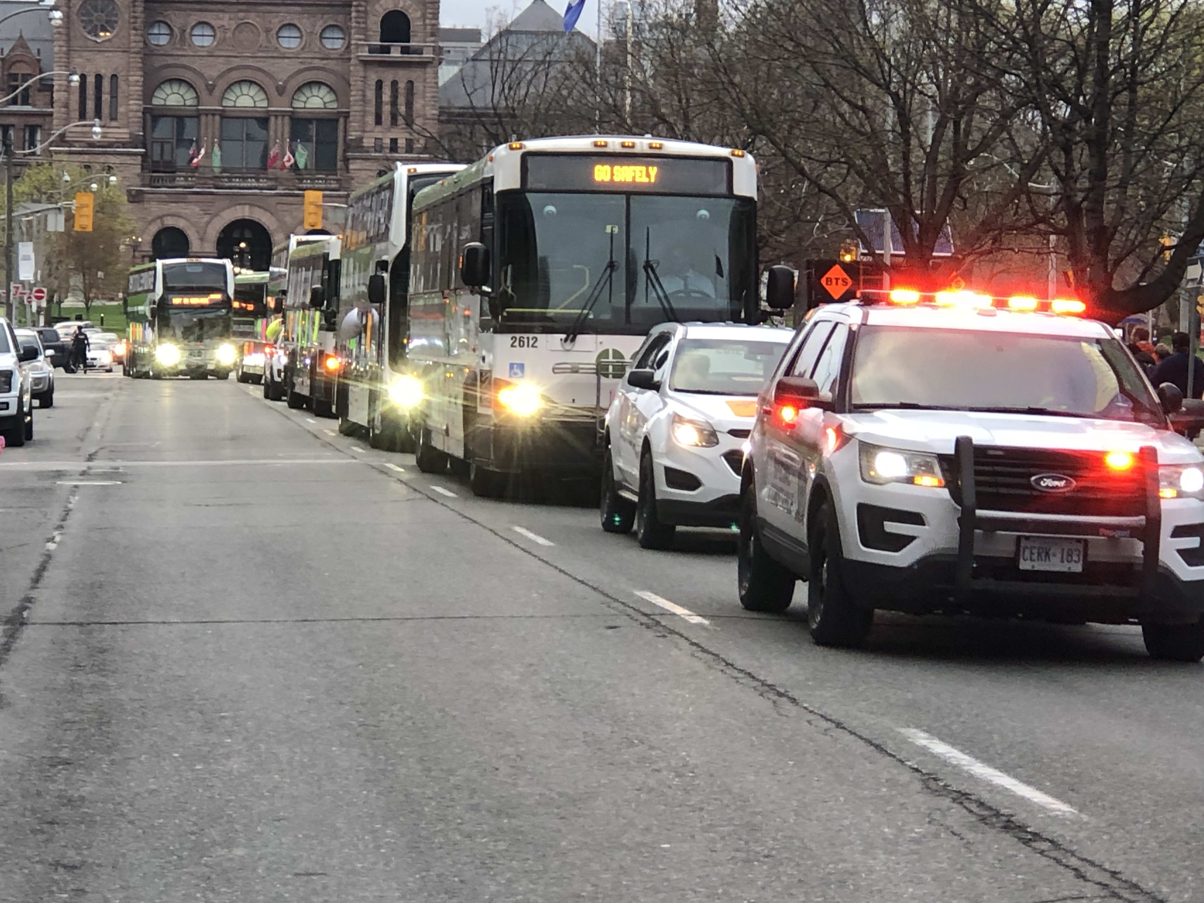 A line of emergency vehicles moves through downtown Toronto.
