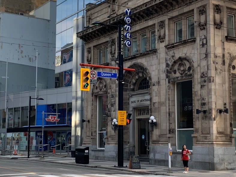 A woman stands at an intersection beside the Bank of Montreal's old building.