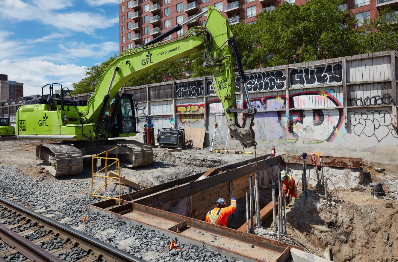 A crew works inside a hole by rail tracks