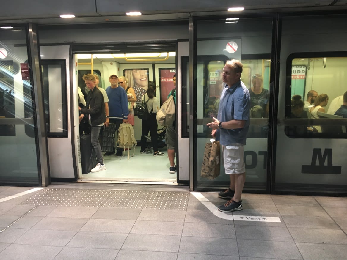 A man stands close to a train, as others wait to go.