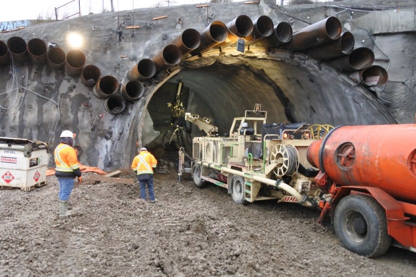 Crews watch as a machine delivers and sprays concrete inside the tunnel.
