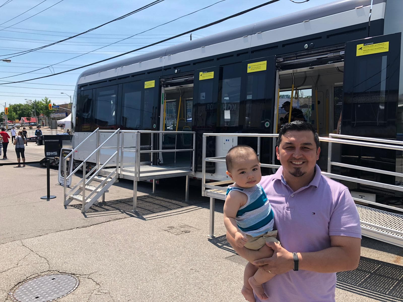 A man holds an infant while next to an LRV mock-up.