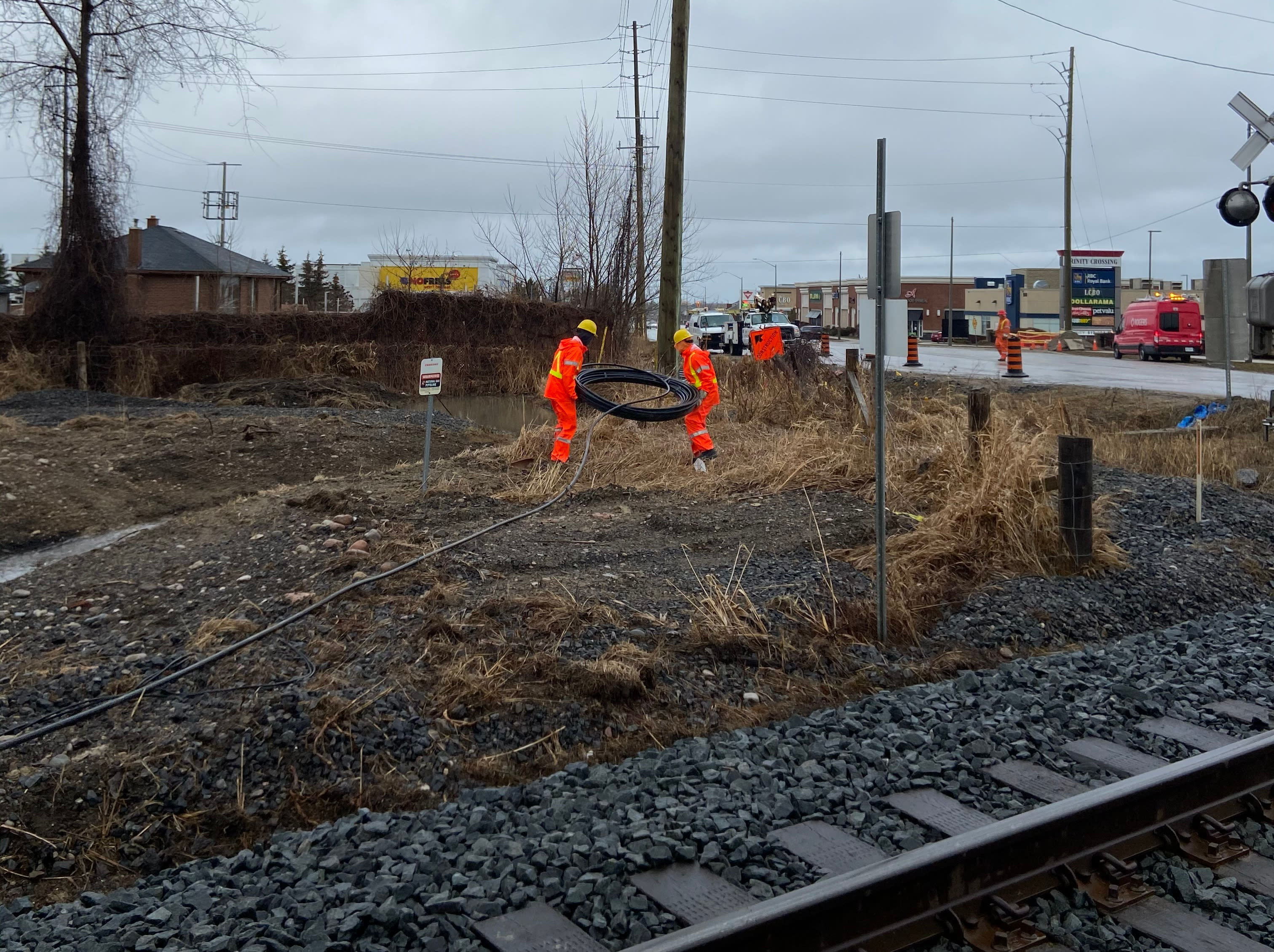 Construction workers run cable near a railway crossing
