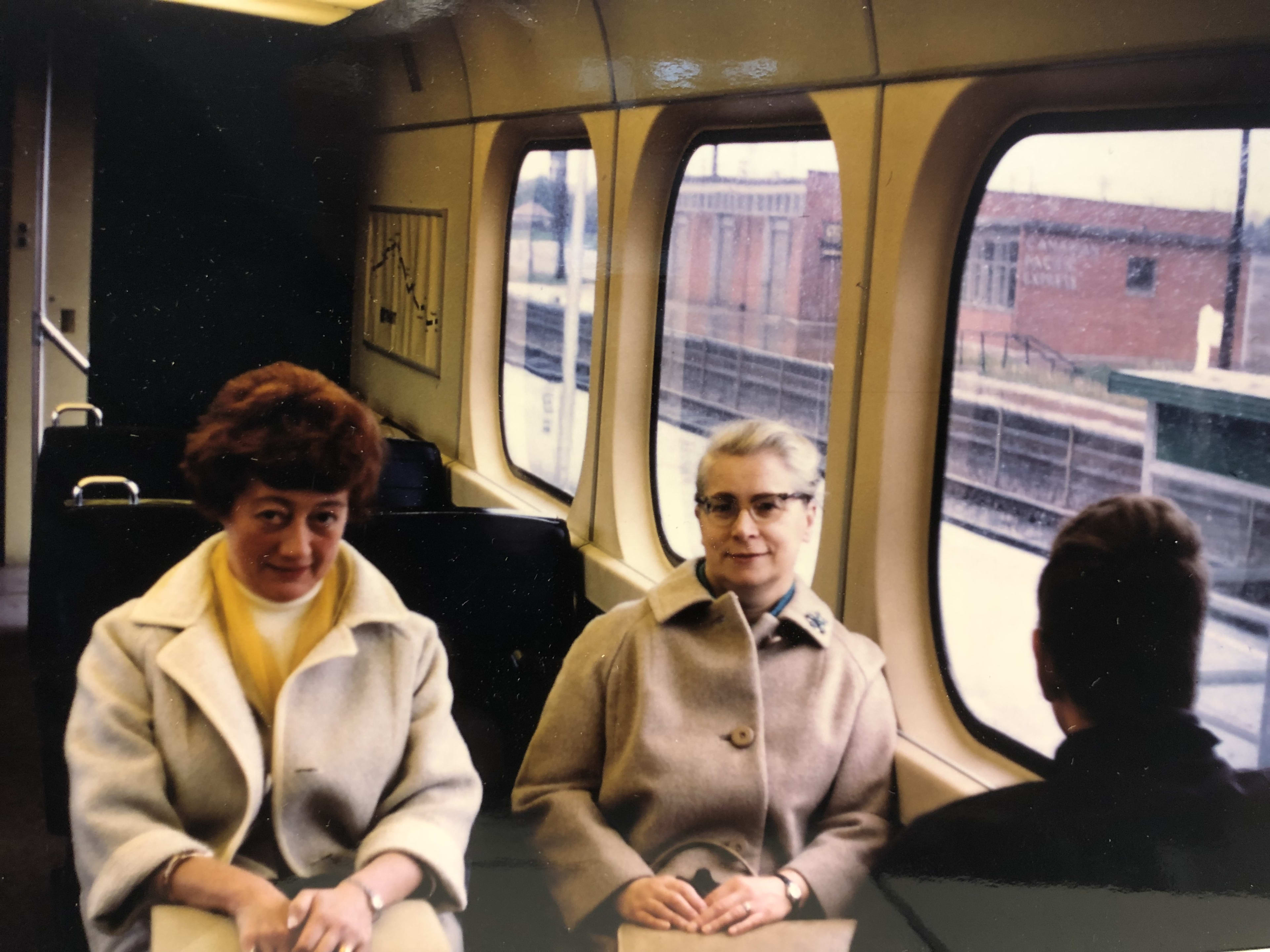 Two women sit next to a man on a GO train.