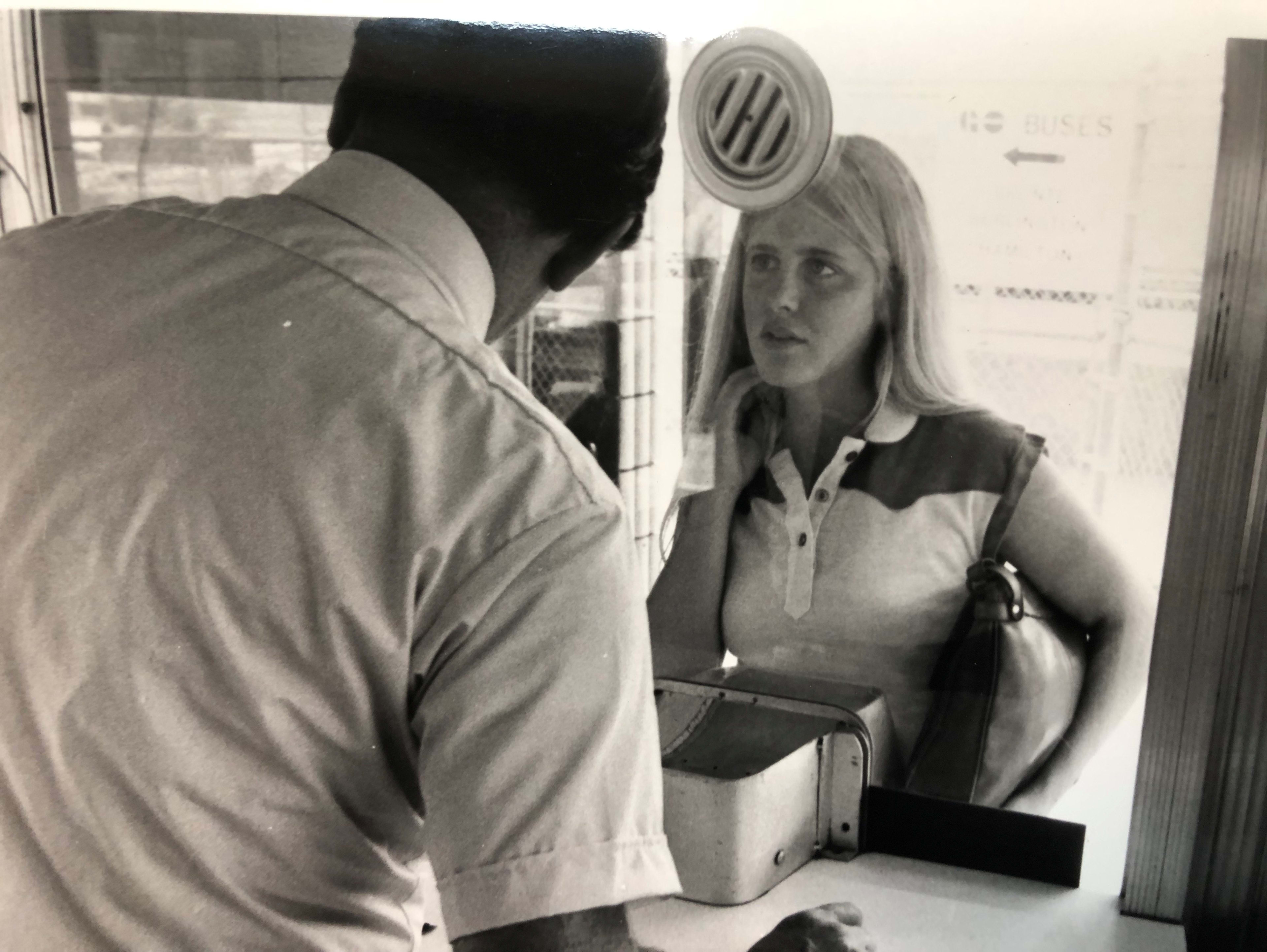 A woman stands in front of a ticket agent.