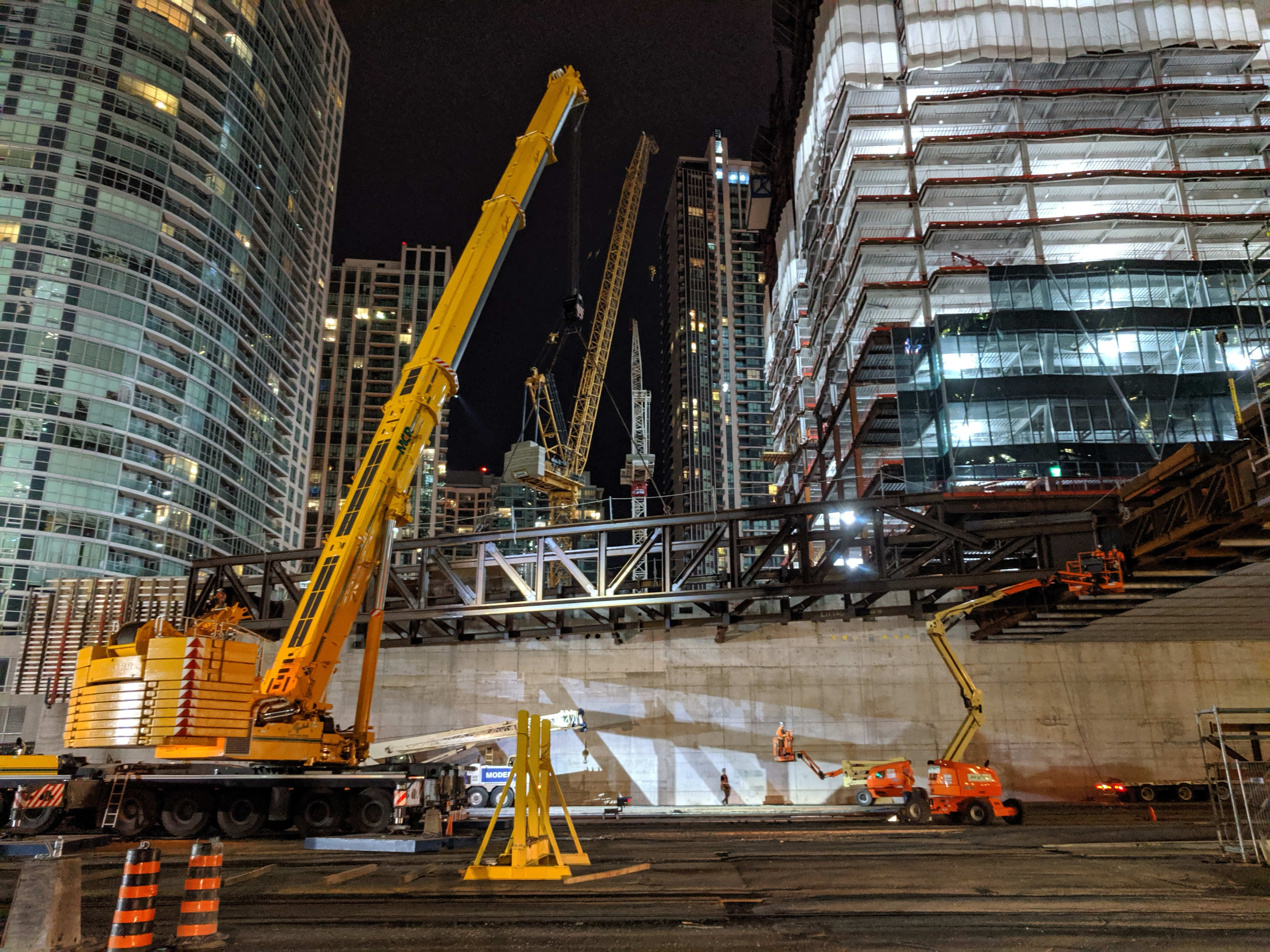 Large crane moves a big piece of metal into place over the tracks.