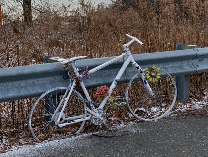 A white painted bike sits next to a guardrail.