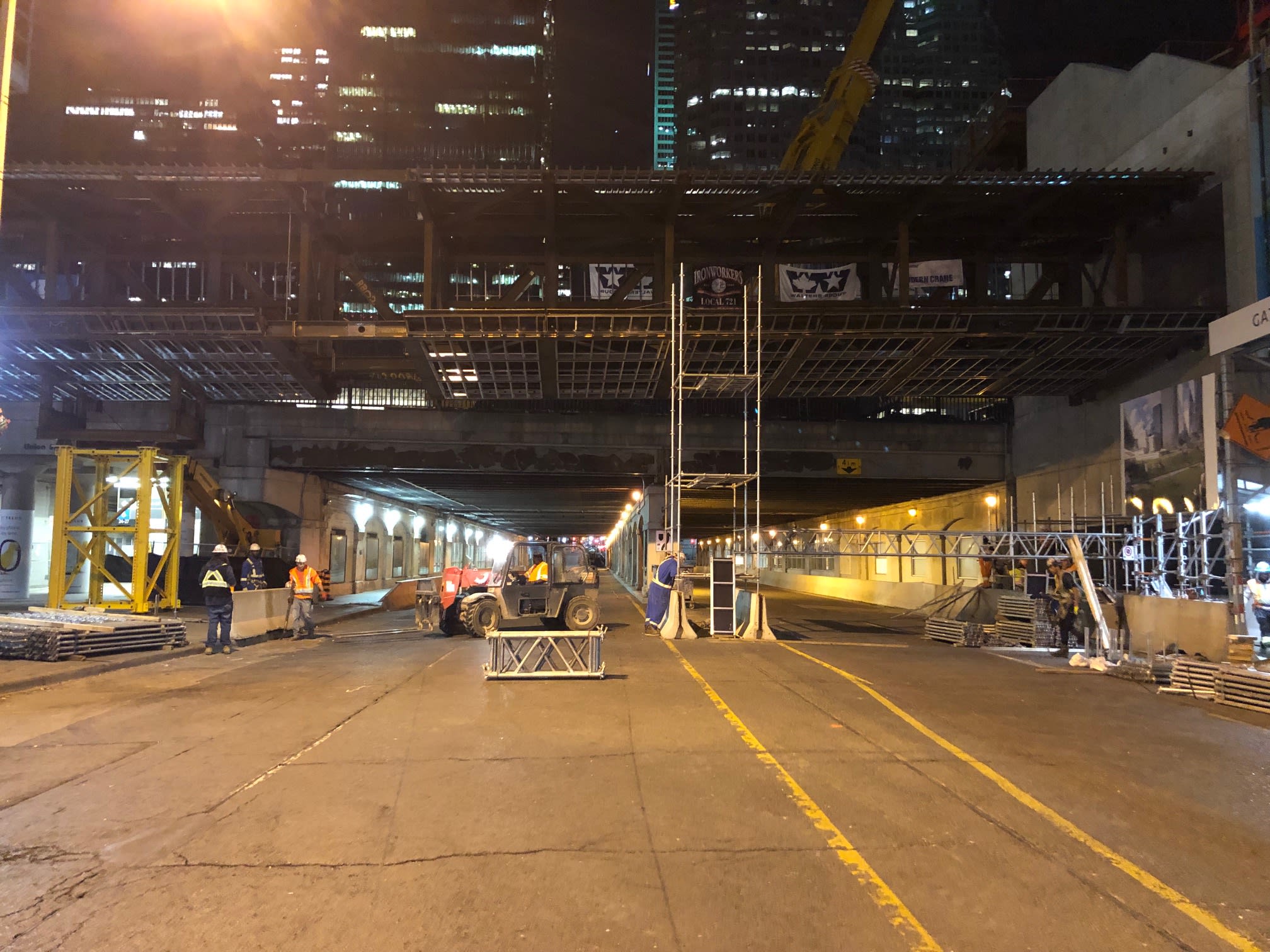 Workers toil under the bridge being put in place over Bay Street.