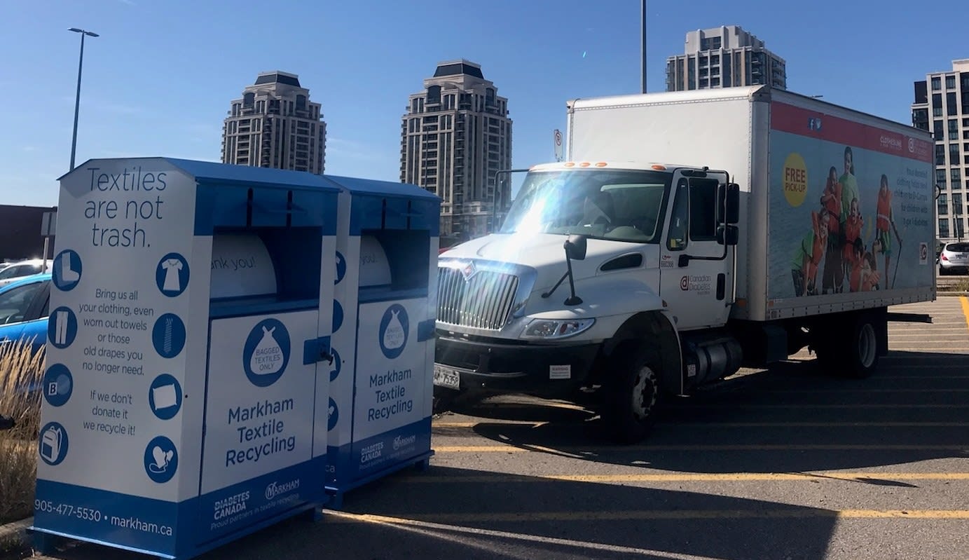 A donations truck is seen parked by two bins.