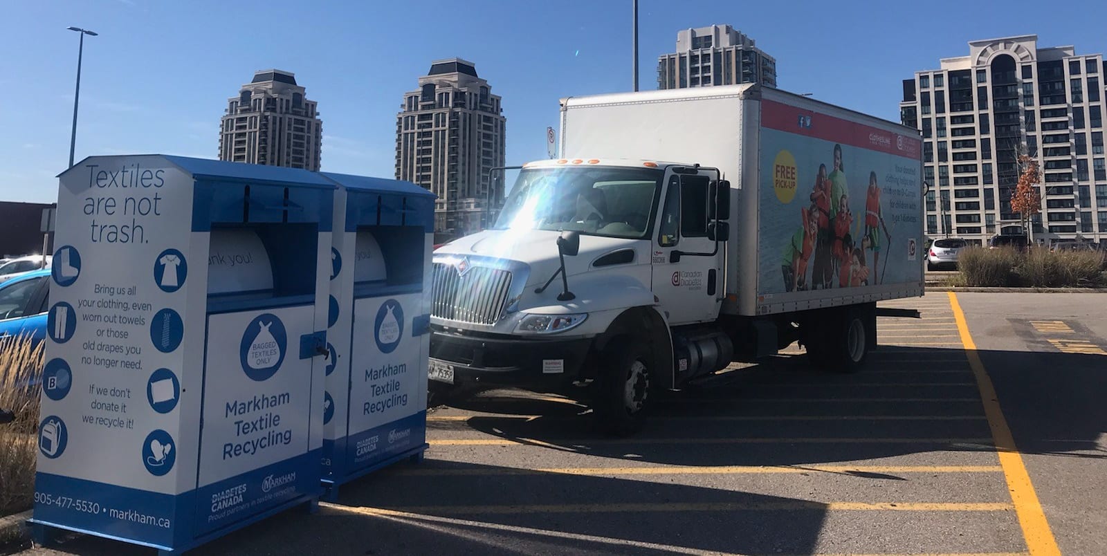 clothing donation bins in the GO Station parking lot with cube van parked next to it