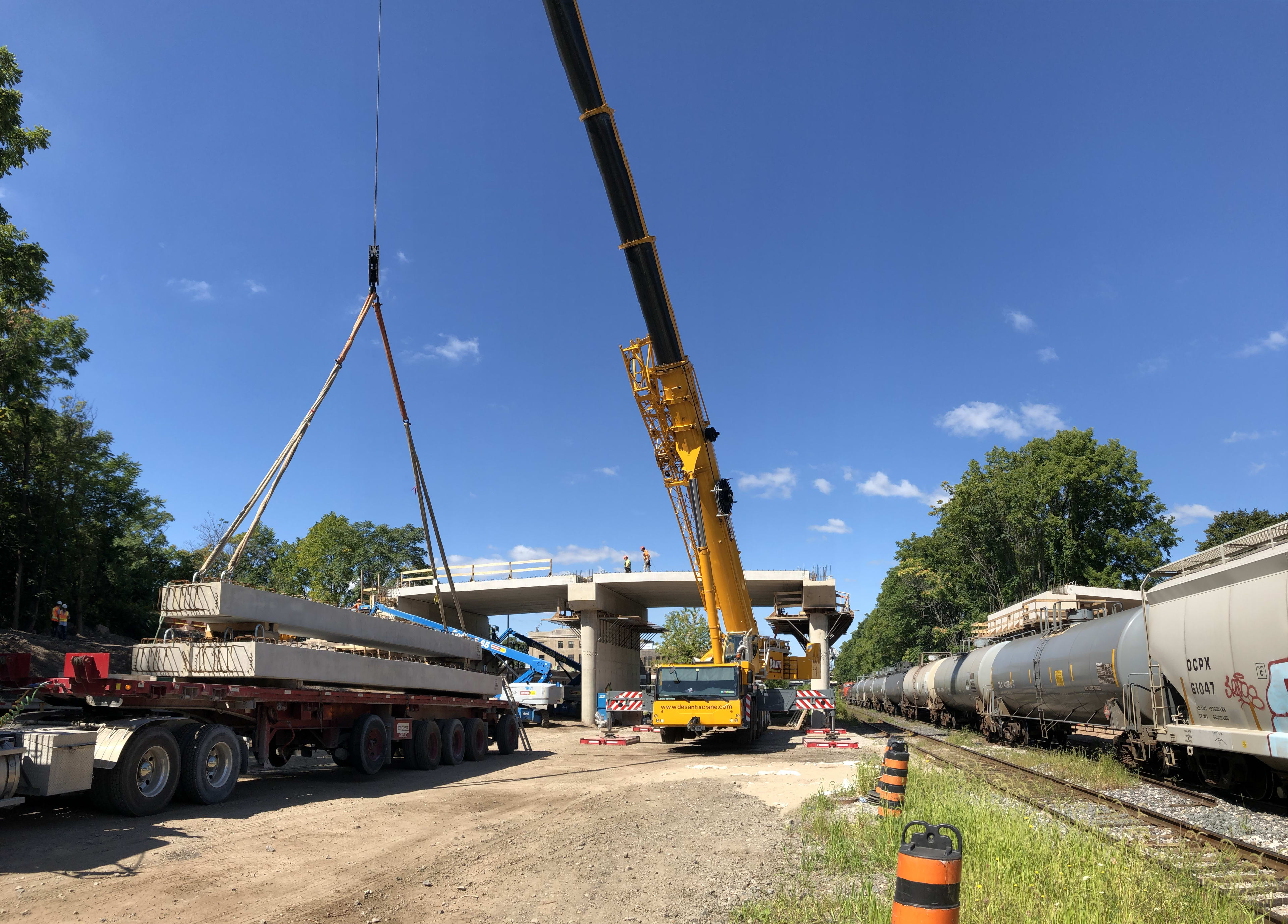 A massive crane lifts a piece of concrete into place during the widening work on the John Street ...